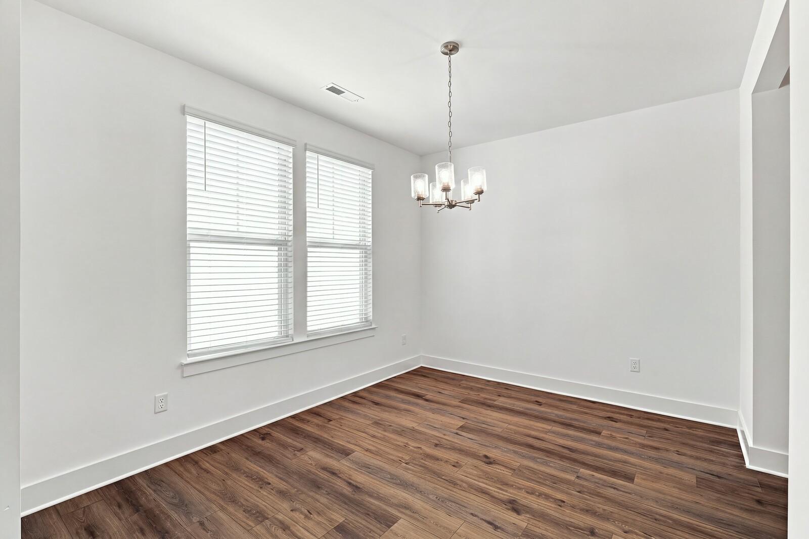 Bright dining room with wood-look flooring, white walls, and chandelier in The Willow C plan at Woods Crossing, Gallatin TN