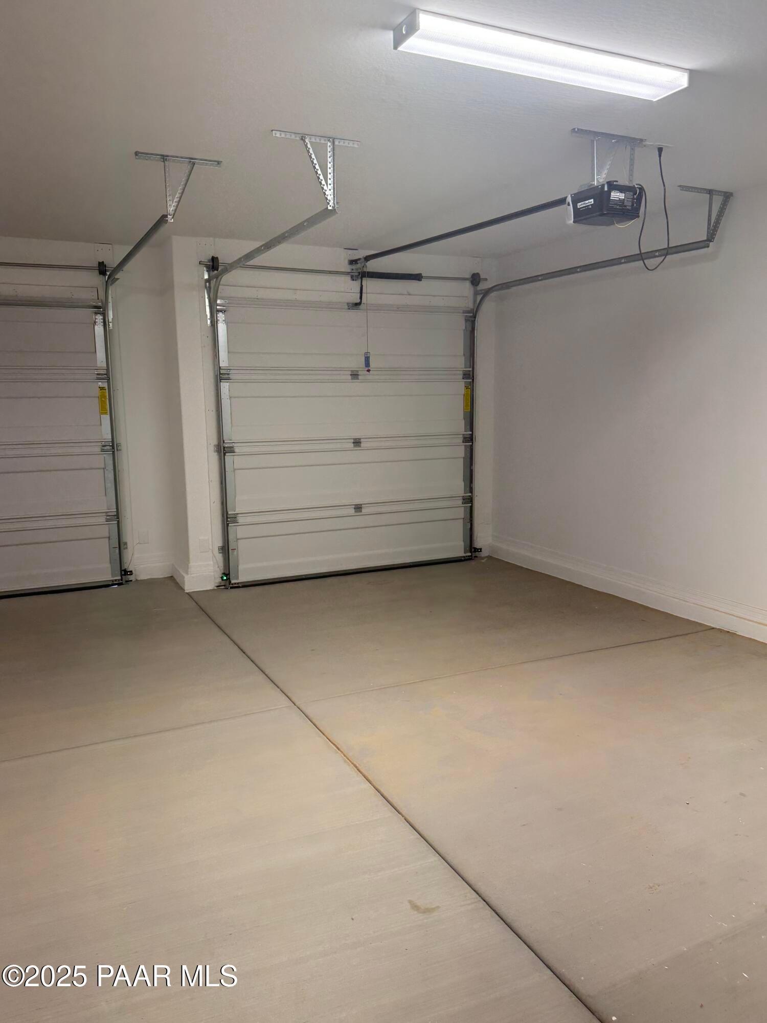 Spacious 3-car garage with white overhead doors, tracks, and LED lighting in Davidson Homes The Monarch E, Prescott, AZ