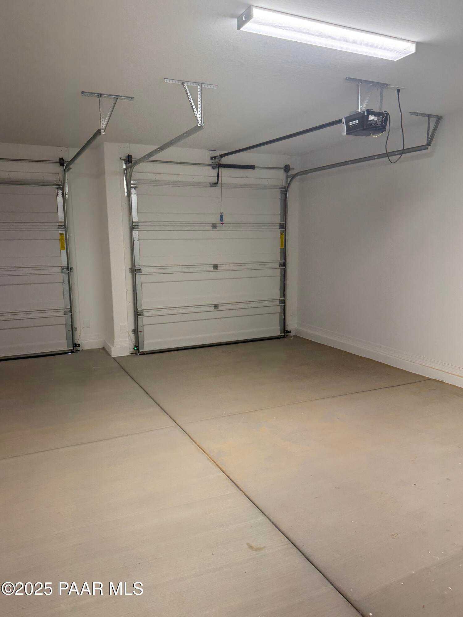 Spacious 3-car garage with white overhead doors, tracks, and LED lighting in Davidson Homes The Monarch E, Prescott, AZ