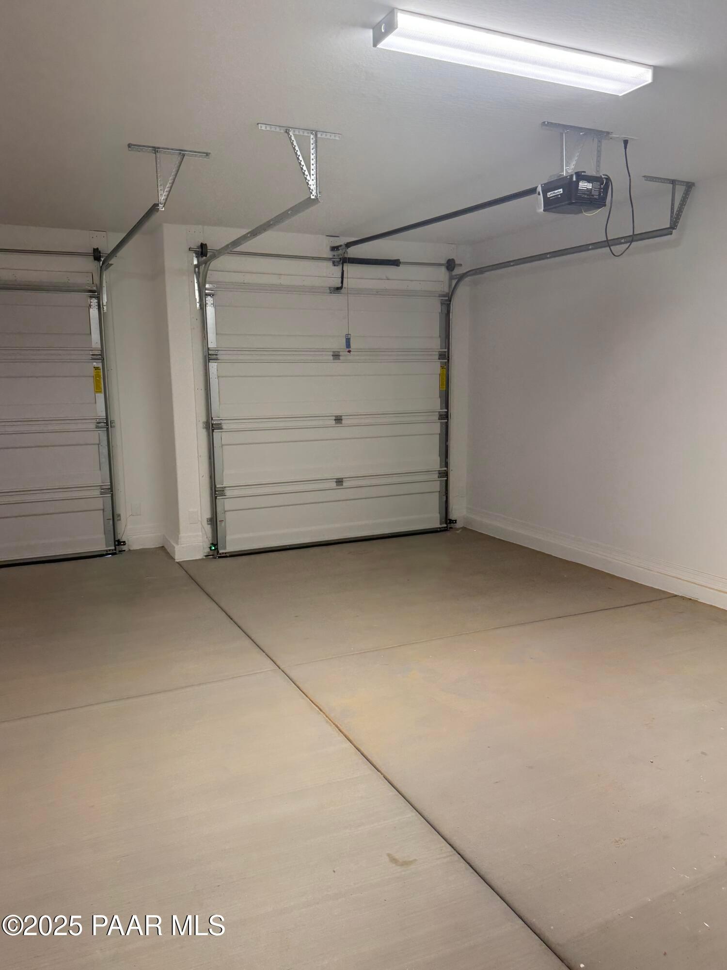 Spacious 3-car garage with white overhead doors, tracks, and LED lighting in Davidson Homes The Monarch E, Prescott, AZ