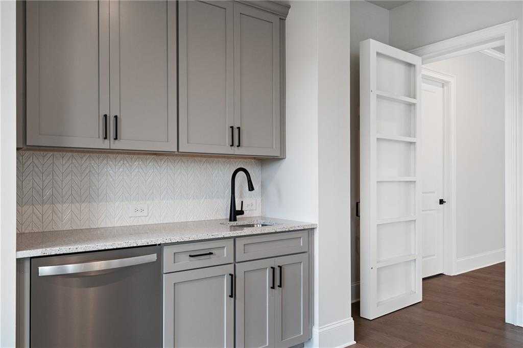 Modern gray shaker kitchen with herringbone tile backsplash, black faucet, and stainless dishwasher in Davidson Homes The Seaside B, Woodstock, GA