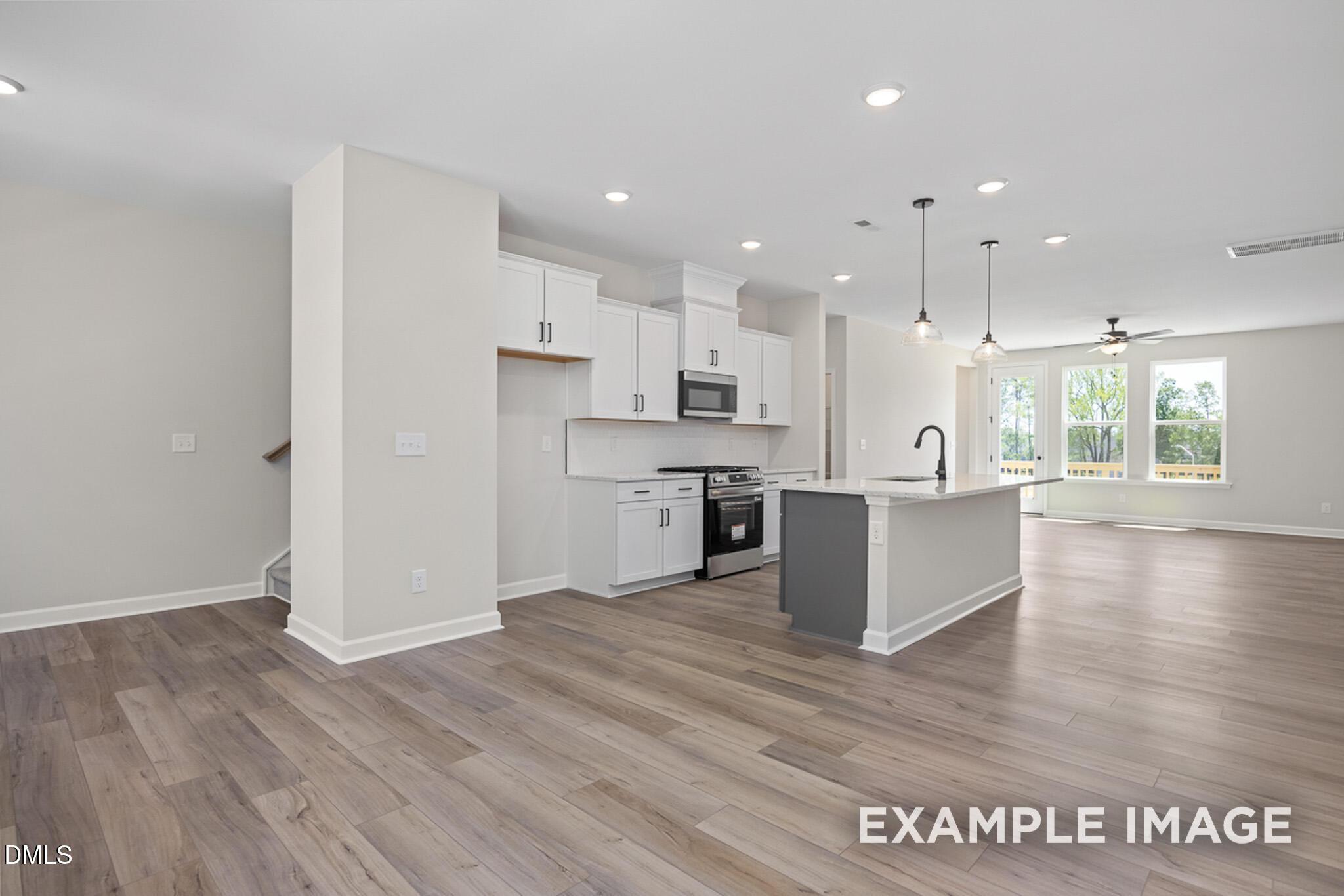 Modern open-concept kitchen with white cabinets and center island in The Mitchell floor plan at Camden Park, Knightdale.