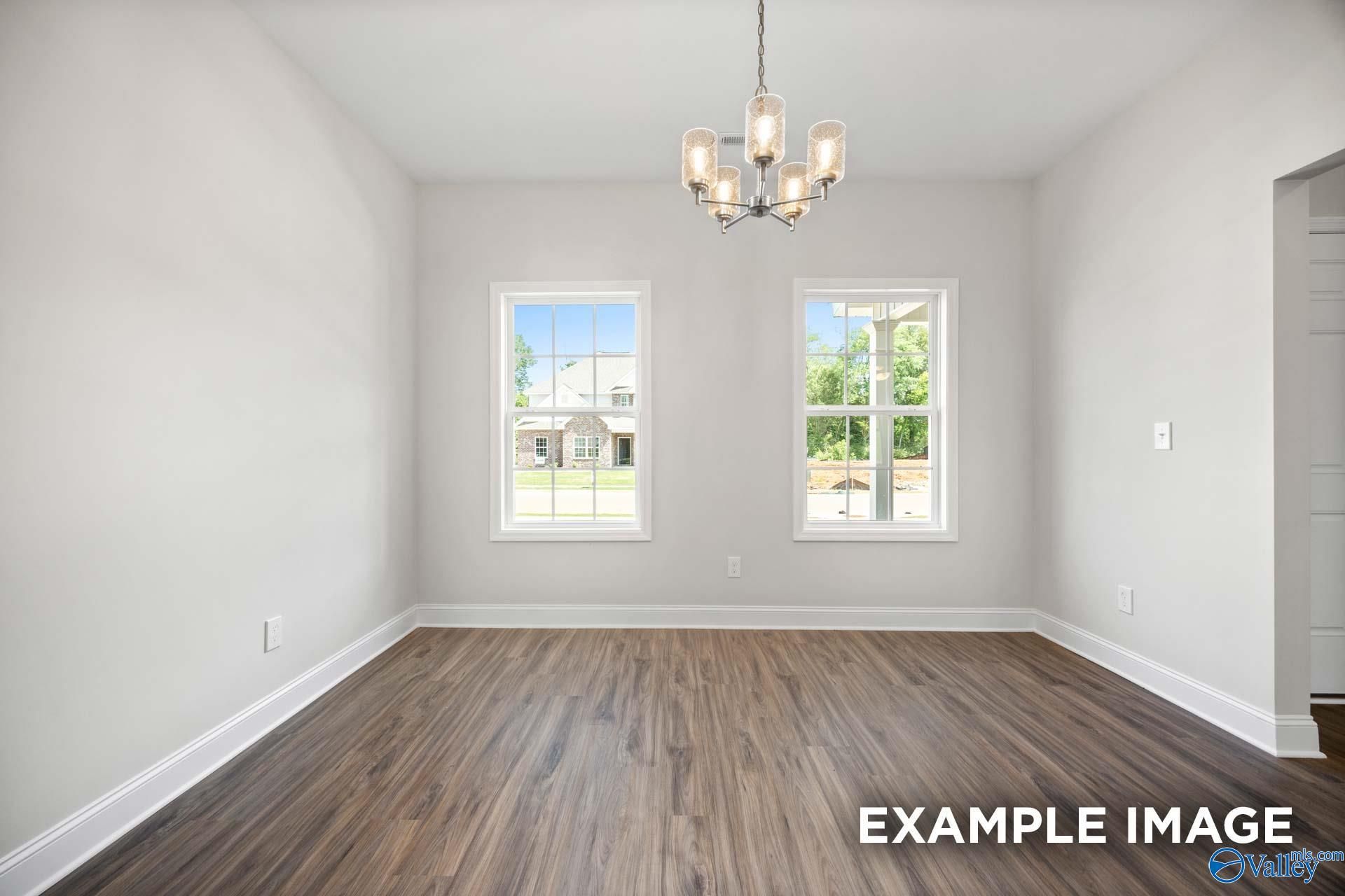 Bright dining room with modern chandelier and wood-look floors in The Shelby B floor plan at Jaguar Hills, Huntsville.
