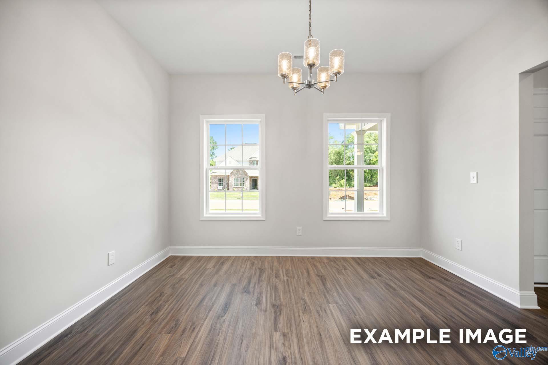 Bright dining room with modern chandelier and wood-look floors in The Shelby B floor plan at Jaguar Hills, Huntsville.