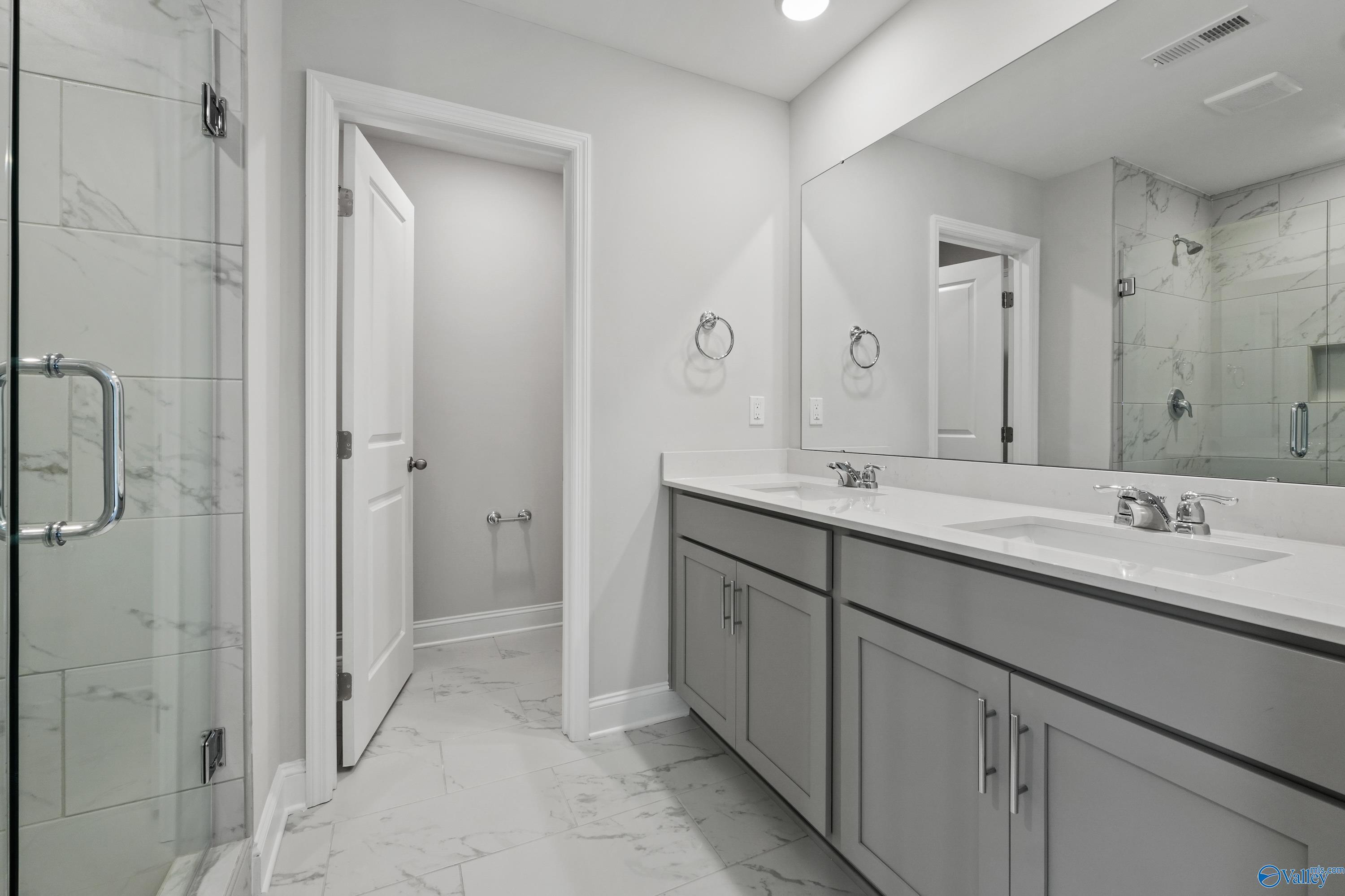 Modern master bathroom featuring frameless glass shower, double gray vanity, and subway tile in Davidson Homes The Camden B, Huntsville