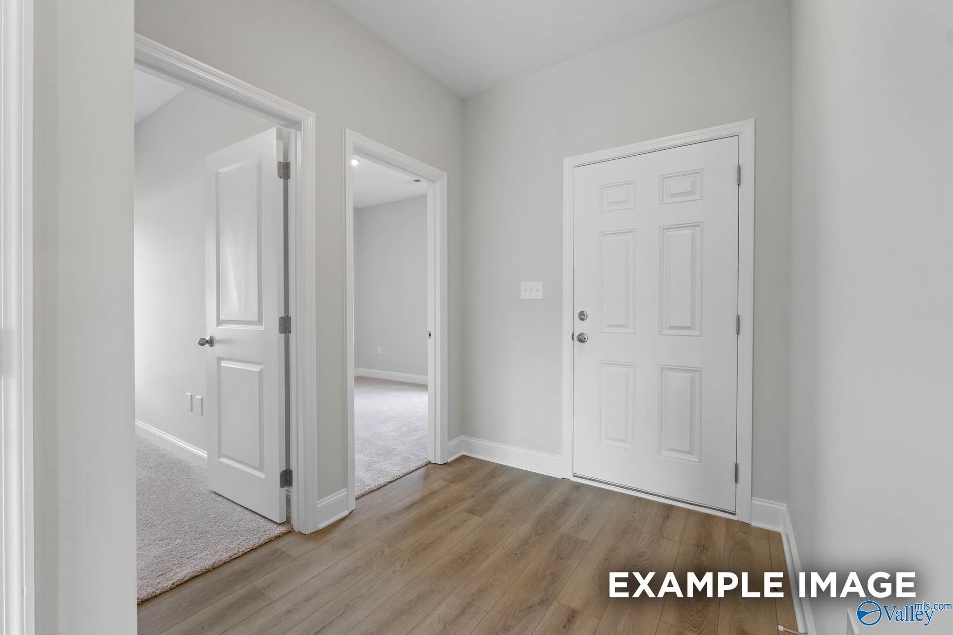 Spacious hallway with gray walls, white paneled doors, hardwood floors, and carpeted rooms in Davidson Homes The Butler, Huntsville AL