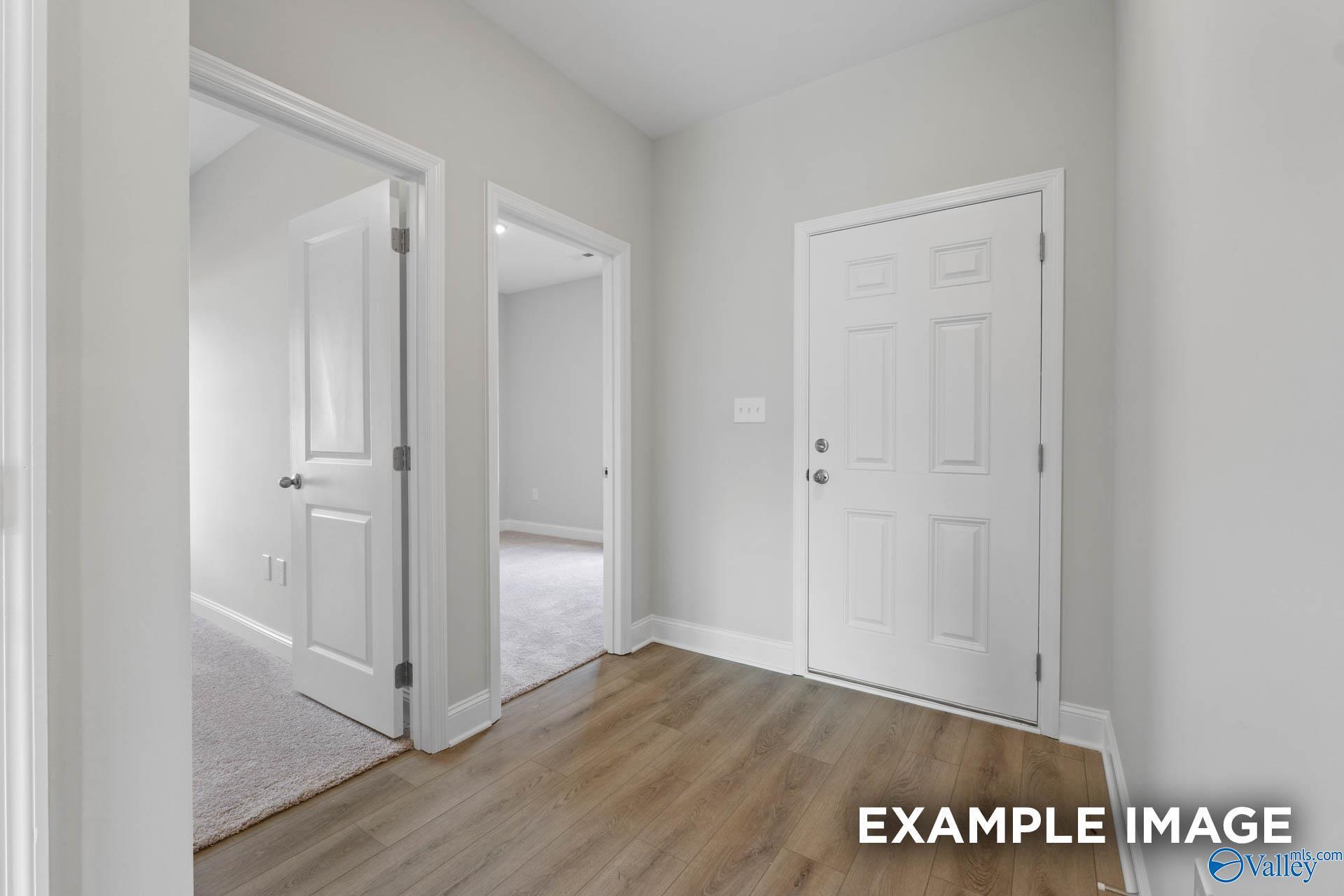 Spacious hallway with white paneled doors, gray walls, and laminate flooring in Davidson Homes The Butler, New Market, Alabama