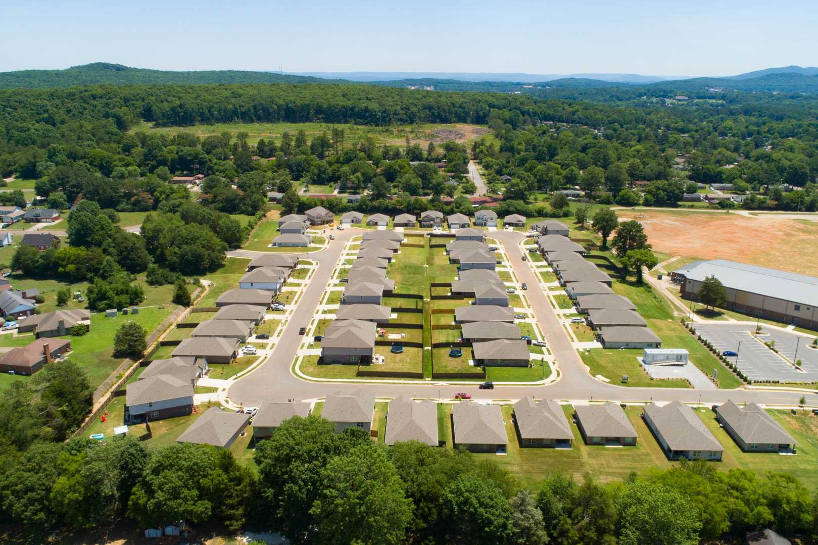Aerial view of new homes in Jaguar Hills, Huntsville Alabama with tree-lined streets and community buildings amid green hills