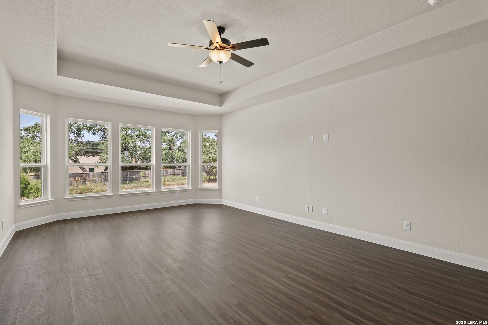 Spacious living area with tray ceiling and bay windows in The Summerlin B floor plan by Davidson Homes in Castroville, TX.