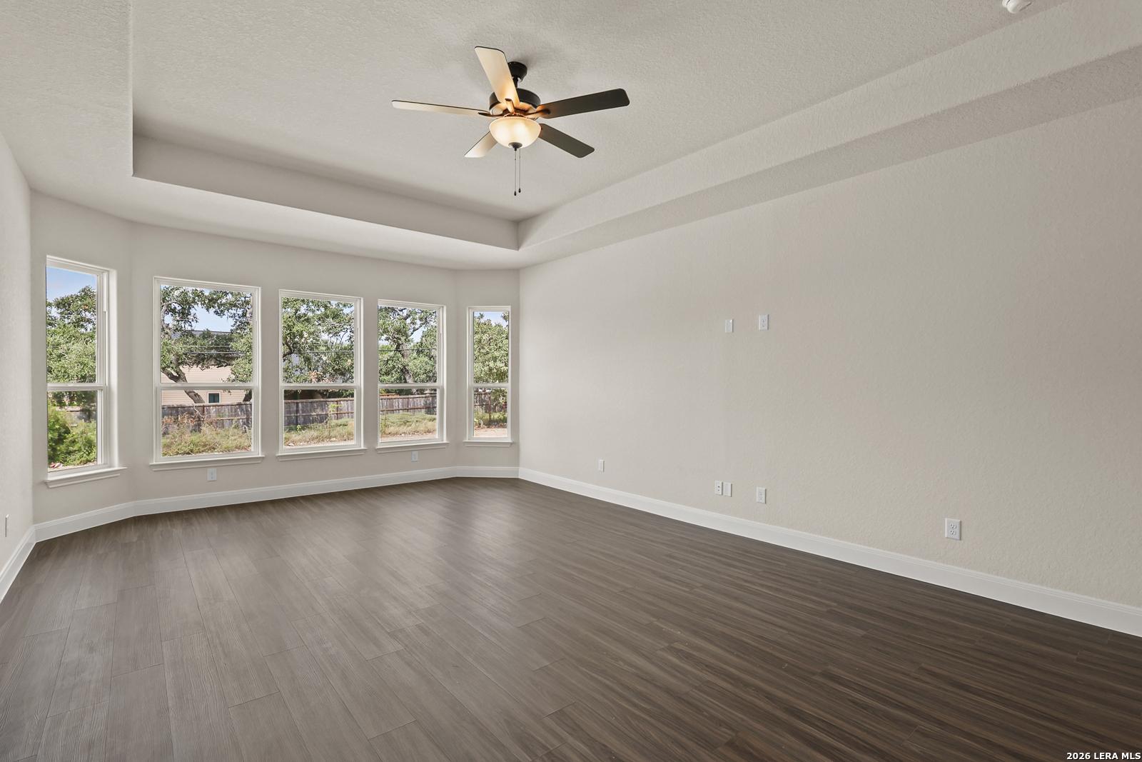 Spacious living area with tray ceiling and bay windows in The Summerlin B floor plan by Davidson Homes in Castroville, TX.