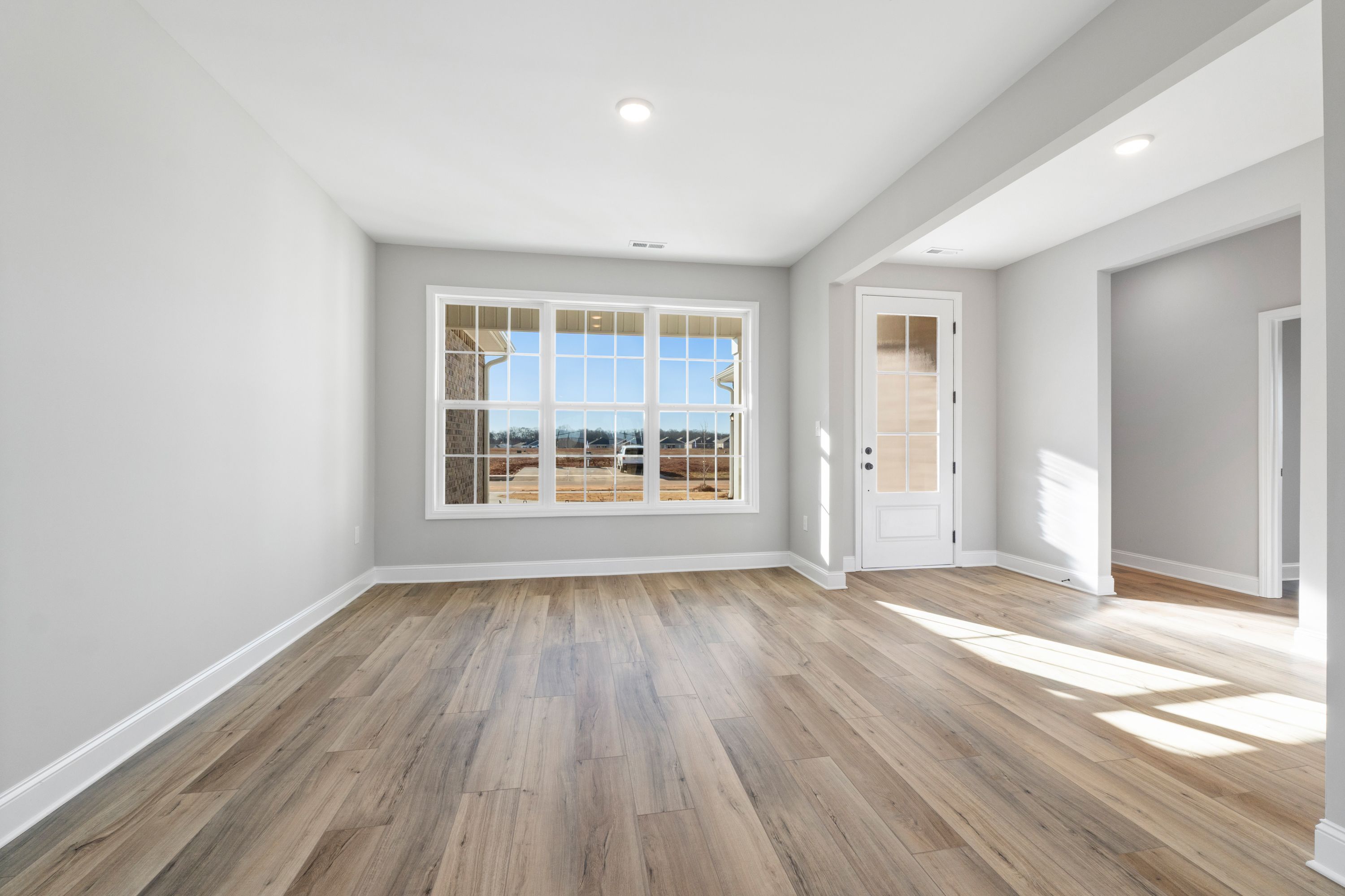 Bright master suite in The Valencia showcasing hardwood floors, large windows, and French doors