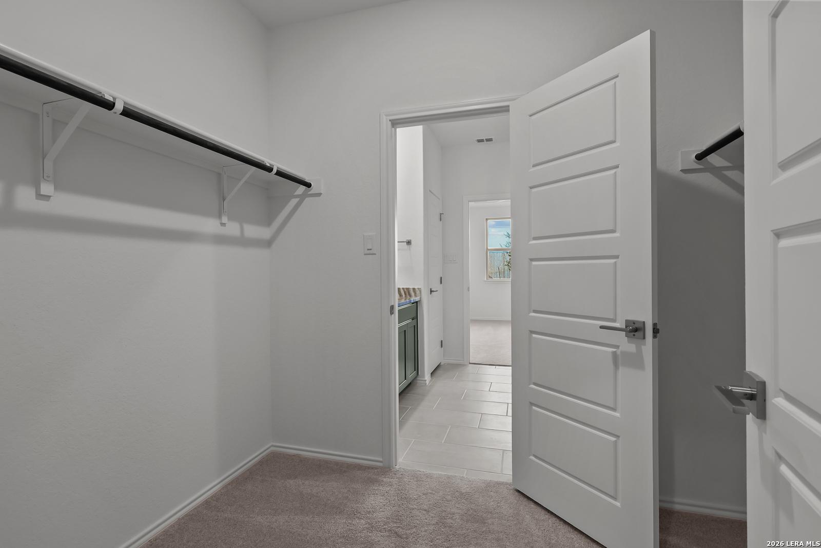 Walk-in closet with carpet and shelving in the Brazos B floor plan by Davidson Homes in Agave, San Antonio, Texas.