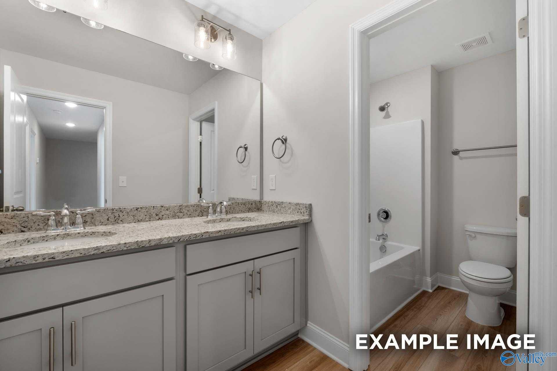 Modern guest bathroom with double granite vanity, gray cabinets, and tub-shower combo in Davidson Homes The Camden, Huntsville AL