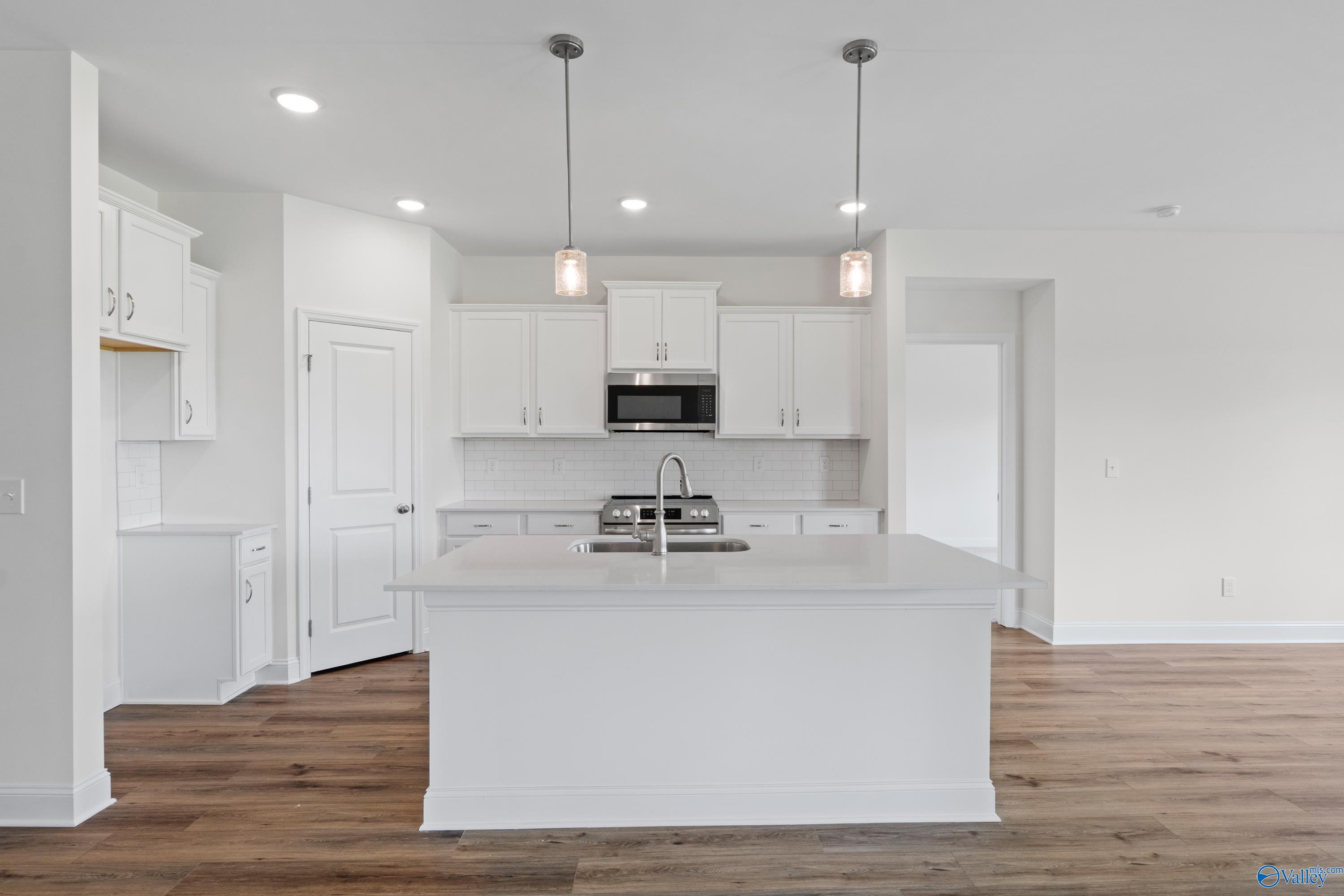 Modern white kitchen with center island and pendant lighting in The Everett B floor plan by Davidson Homes in Athens, AL.