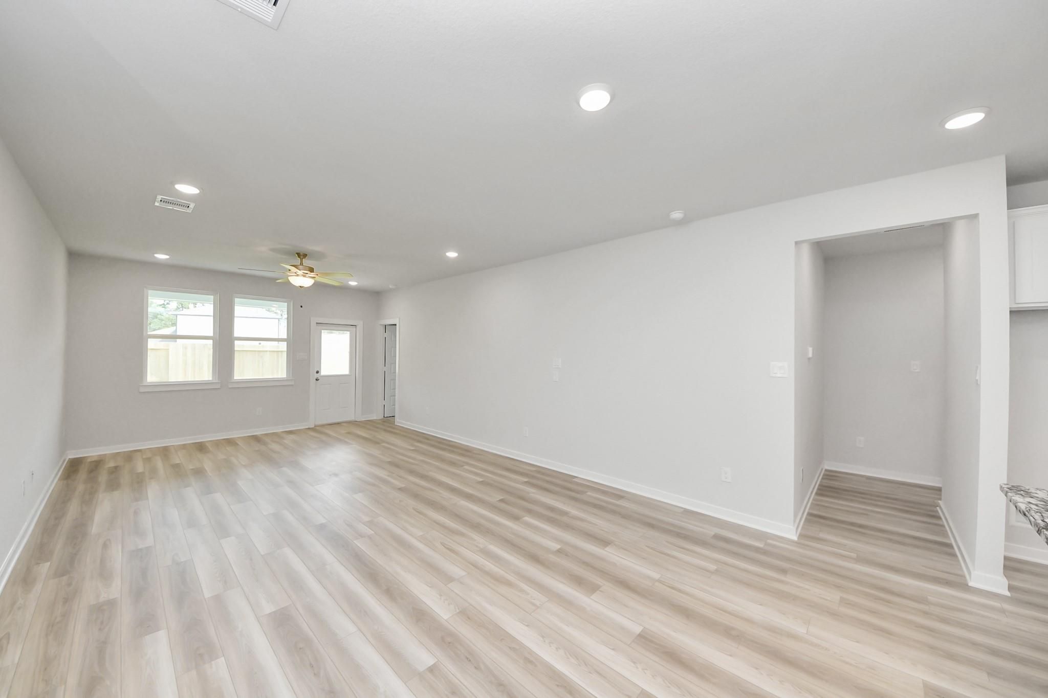 Spacious open-concept living area with wood-look flooring in The Sabine F floor plan at Liberty Estates, Cleveland, Texas.