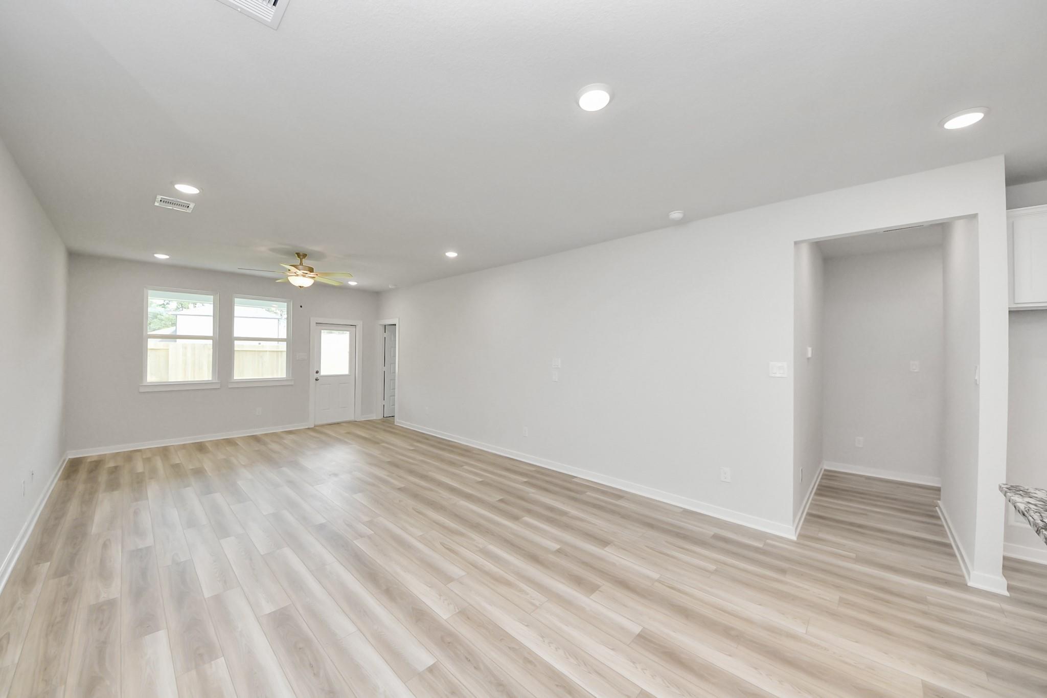 Spacious open-concept living area with wood-look flooring in The Sabine F floor plan at Liberty Estates, Cleveland, Texas.