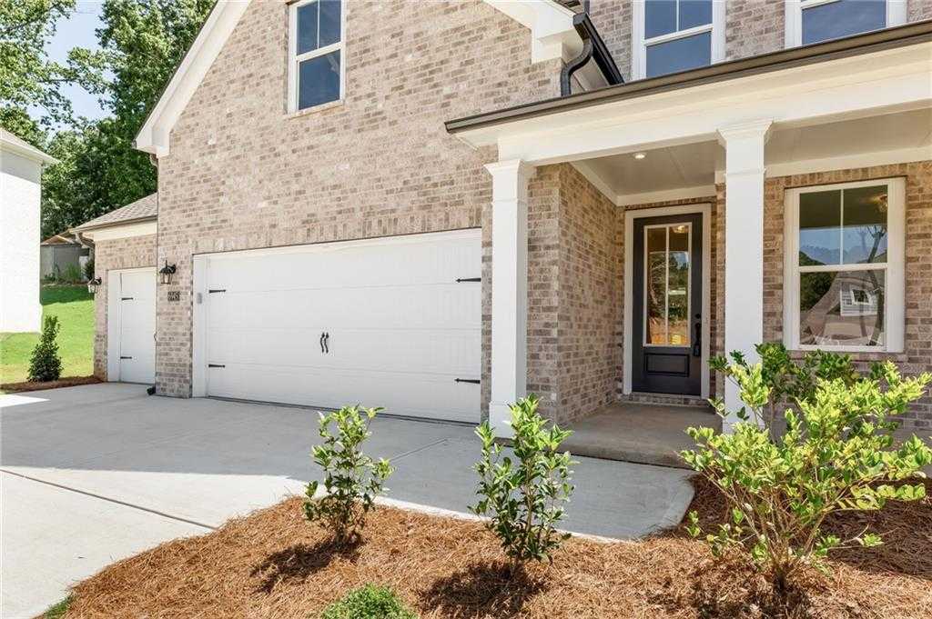 Brick two-story home with columned porch, 3-car garage, and landscaped entry in Melody Lakeside Estates, Buford, Georgia