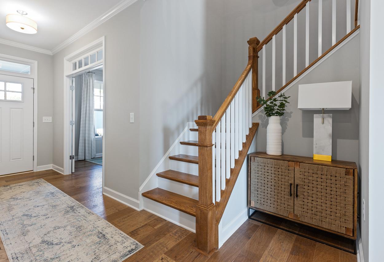 Foyer of The Hemlock A featuring hardwood floors, a wooden staircase, and a decorative console table in Belmont, NC.