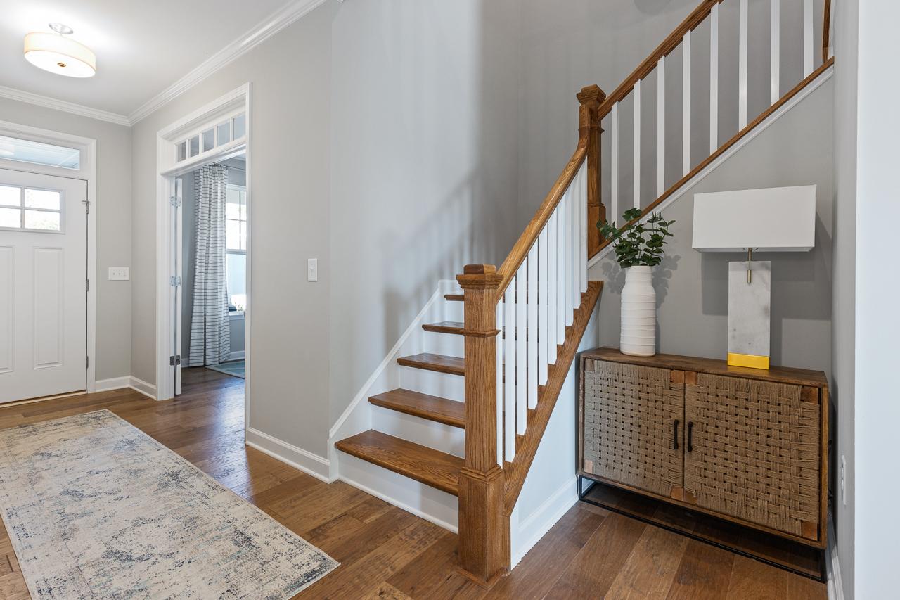 Foyer of The Hemlock A featuring hardwood floors, a wooden staircase, and a decorative console table in Belmont, NC.