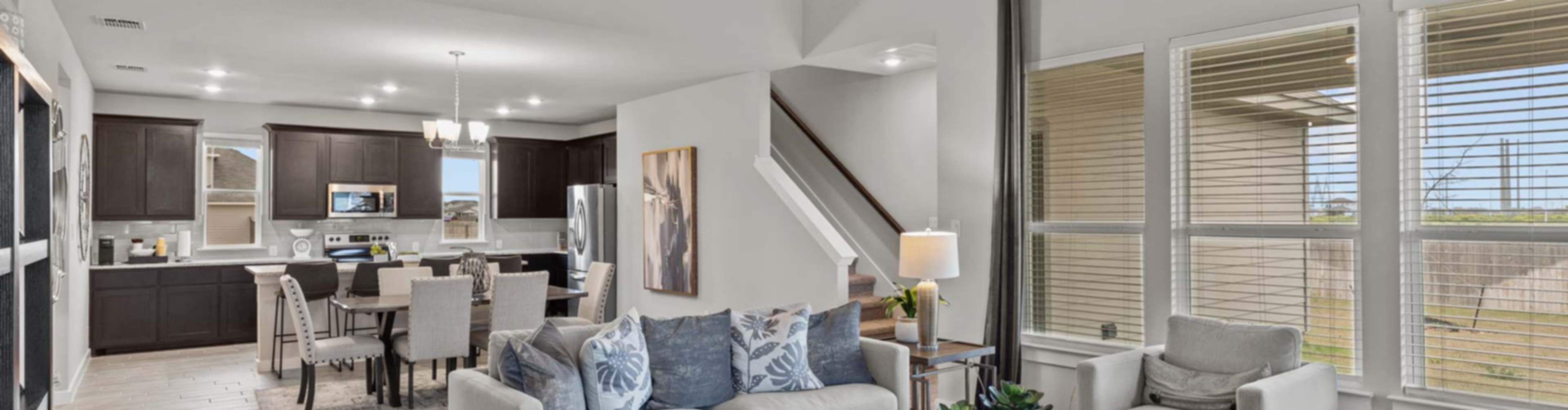 Modern open-concept living room with gray sofa, kitchen, and dining area in new Seguin home