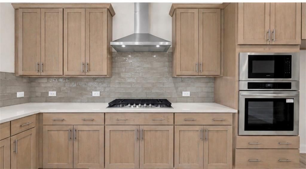 Modern kitchen with wood cabinets, stainless steel appliances, and tile backsplash in The Hickory C home, Wehunt Meadows.