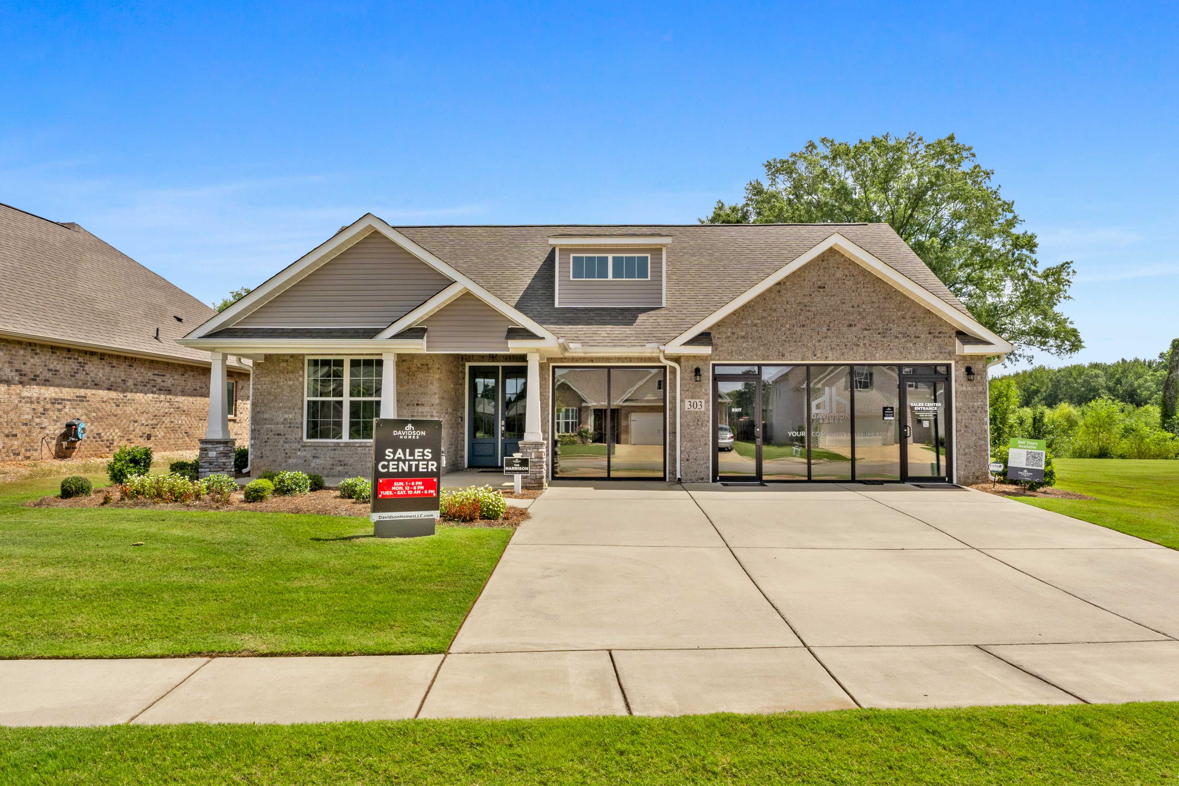 Sales office model home exterior at Kendall Downs in Toney Alabama with gray siding large windows and manicured lawn