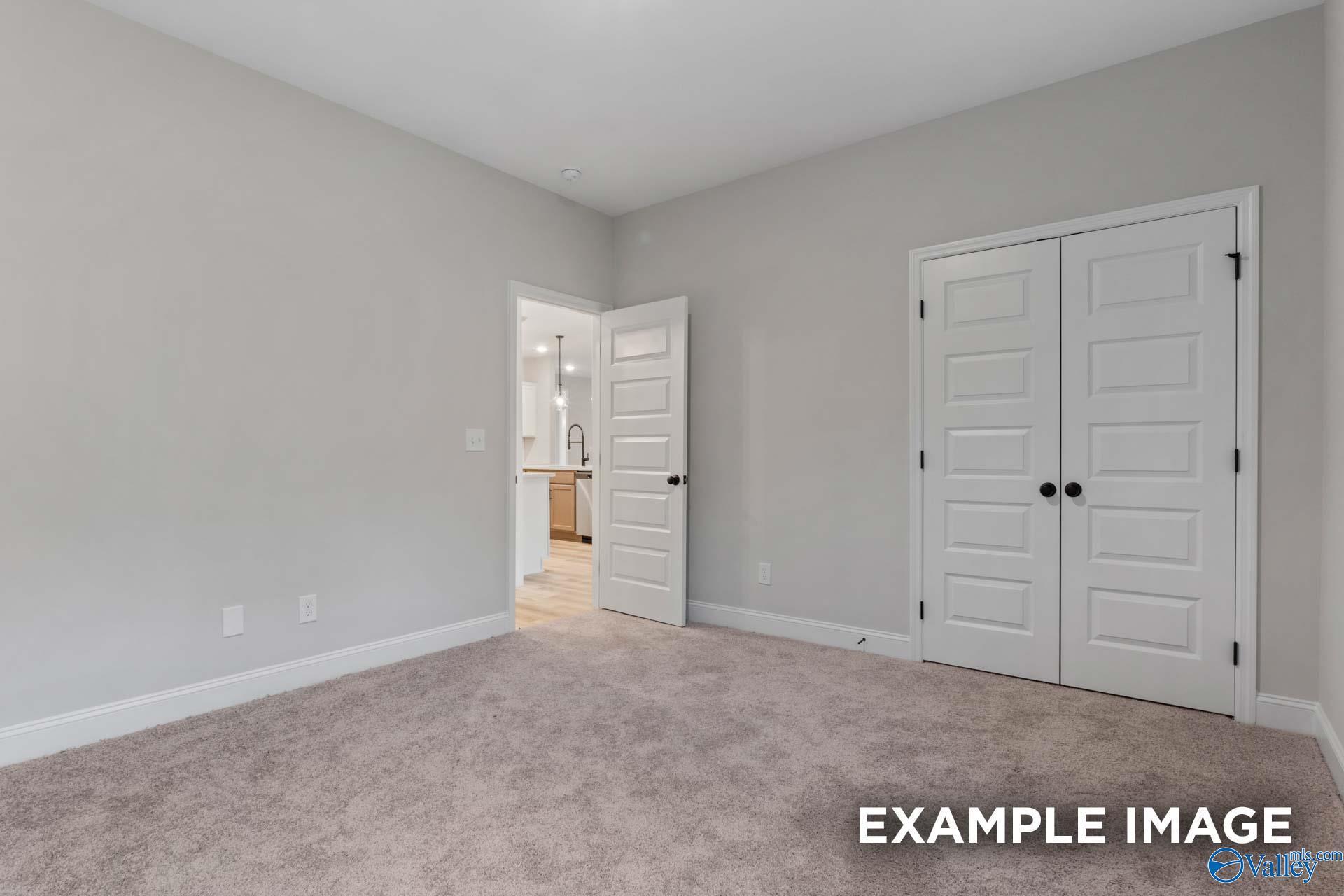 Spacious bedroom featuring double closet doors and en-suite bath access in Davidson Homes The Finleigh, Meridianville, Alabama