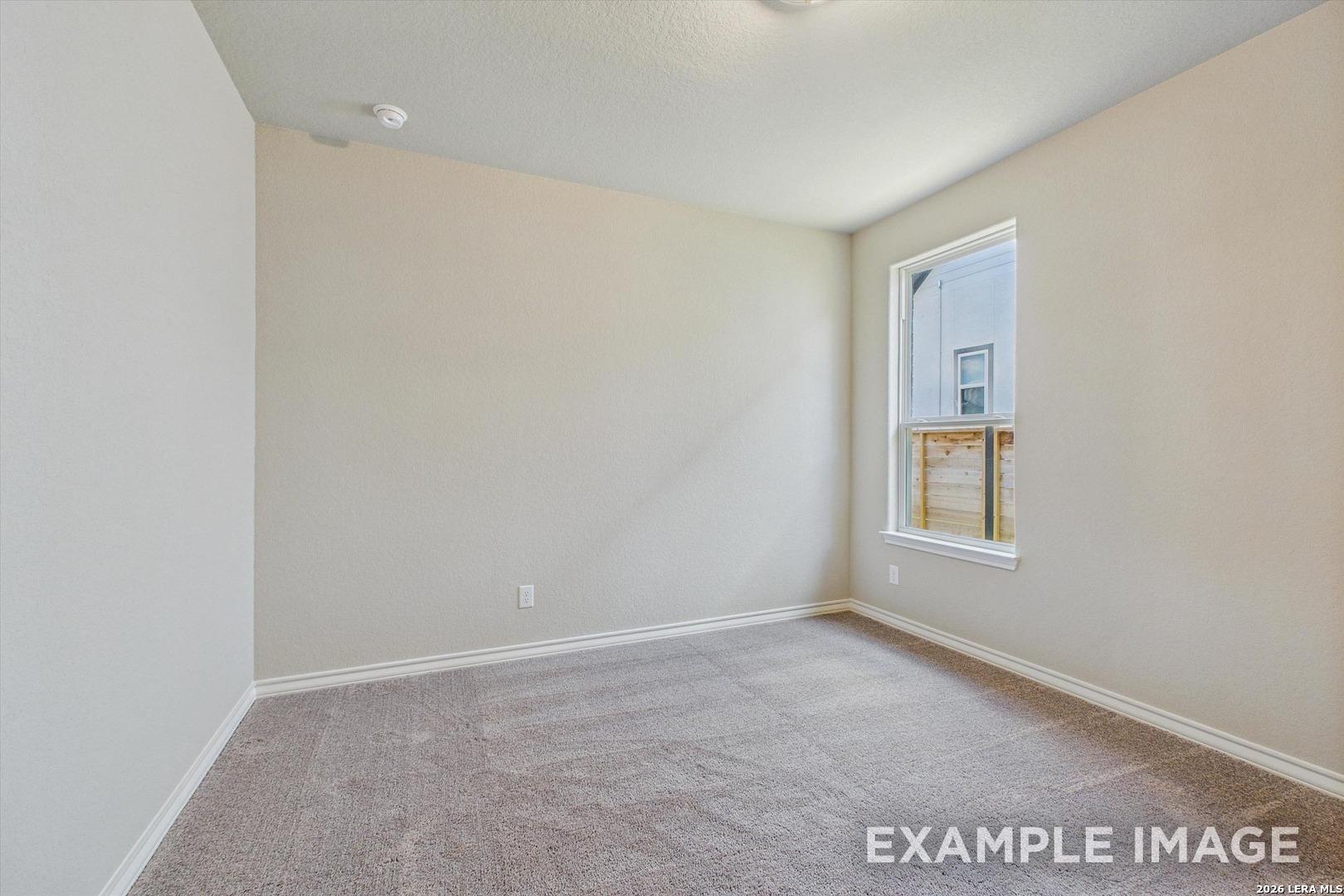 Spacious secondary bedroom with neutral carpet and paint in The Foster F floor plan at Potranco Oaks, Castroville, Texas.