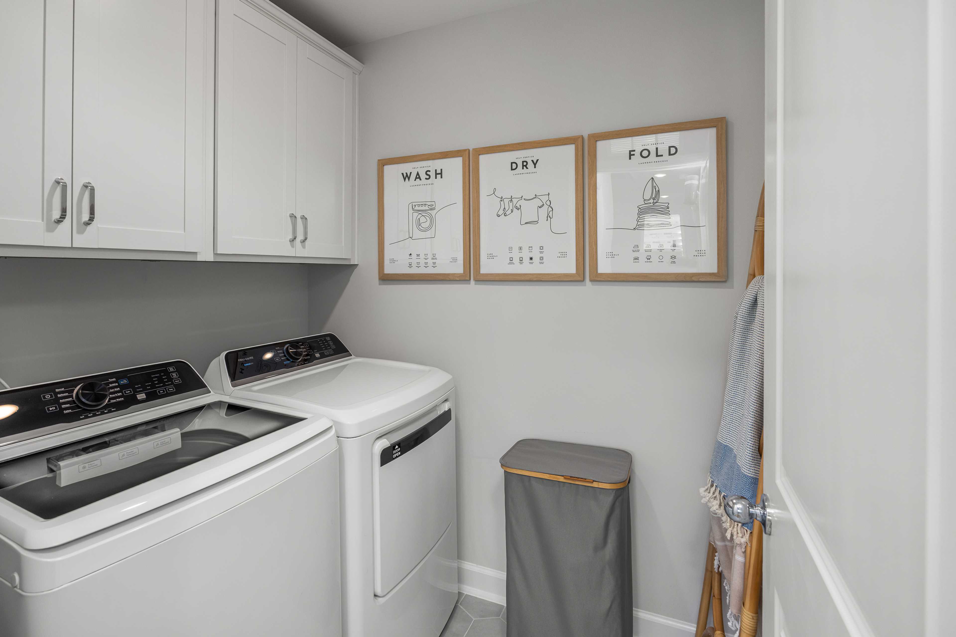 Spacious laundry room in Springvale Fuquay-Varina NC by Davidson Homes with white washer dryer and WASH DRY FOLD wall art