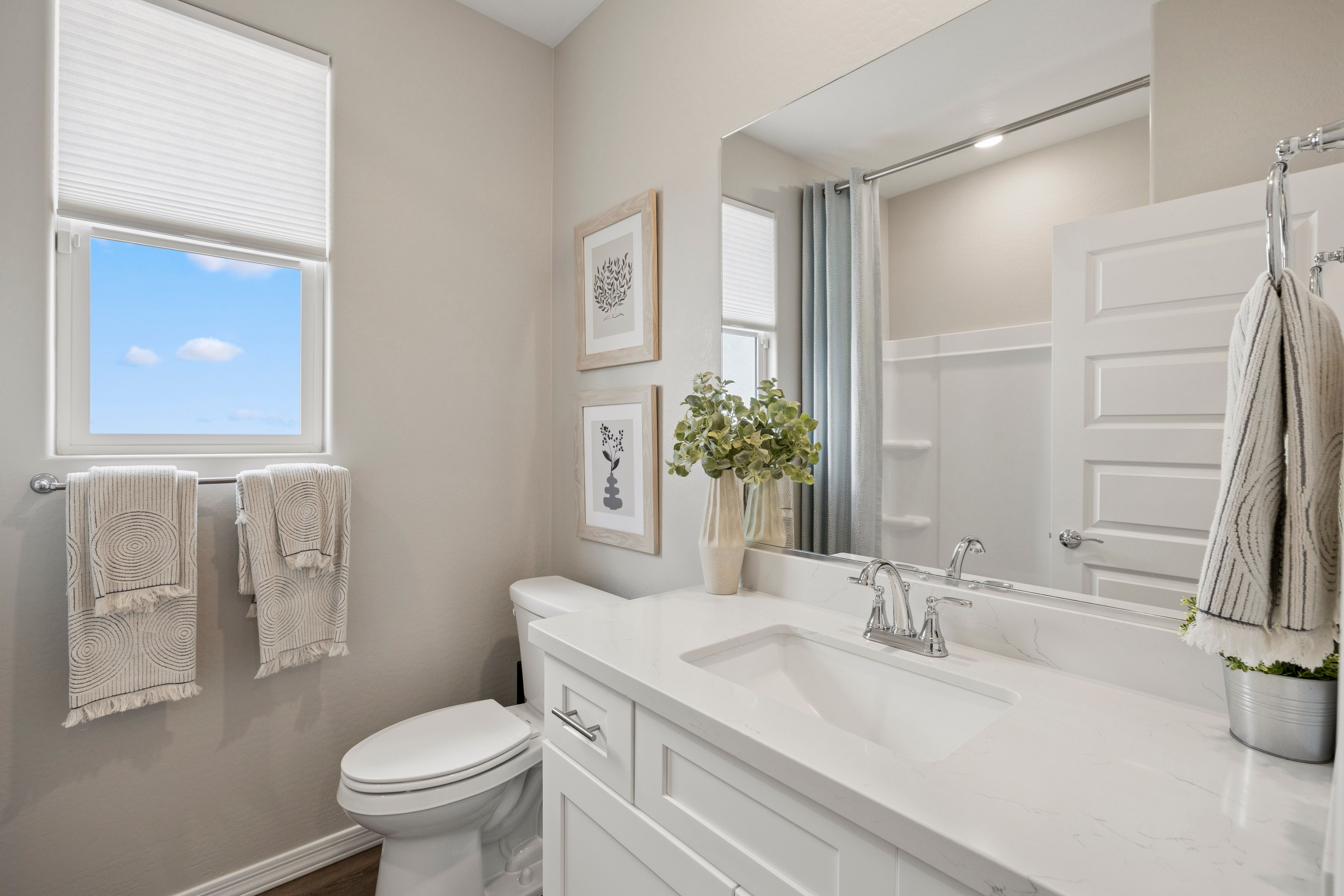 Bright bathroom at South Ranch Destination Collection in Prescott AZ with white quartz vanity, large mirror, walk-in shower