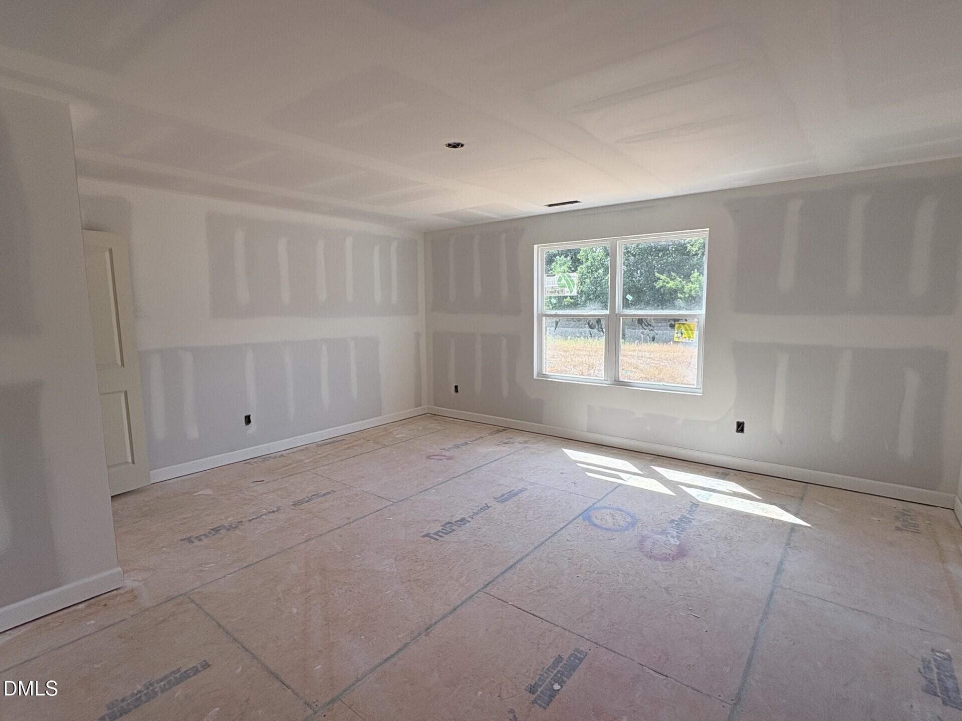 Unfinished bedroom with drywall and subflooring in The Ash C floor plan at Woodland Crossing in Zebulon, North Carolina.