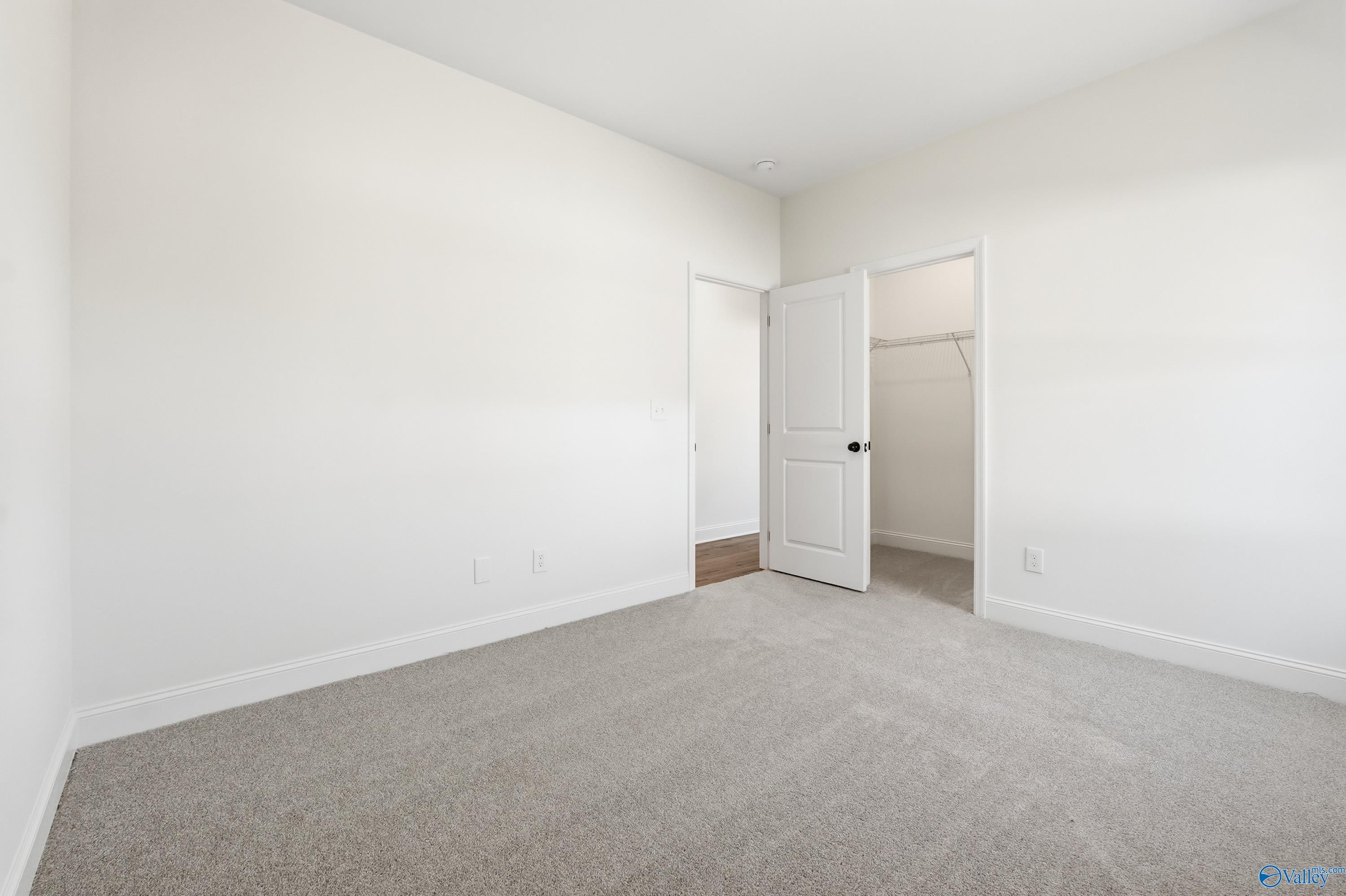 Bright bedroom with open walk-in closet door and neutral carpet in Davidson Homes The Rockford D, Hazel Green, Alabama