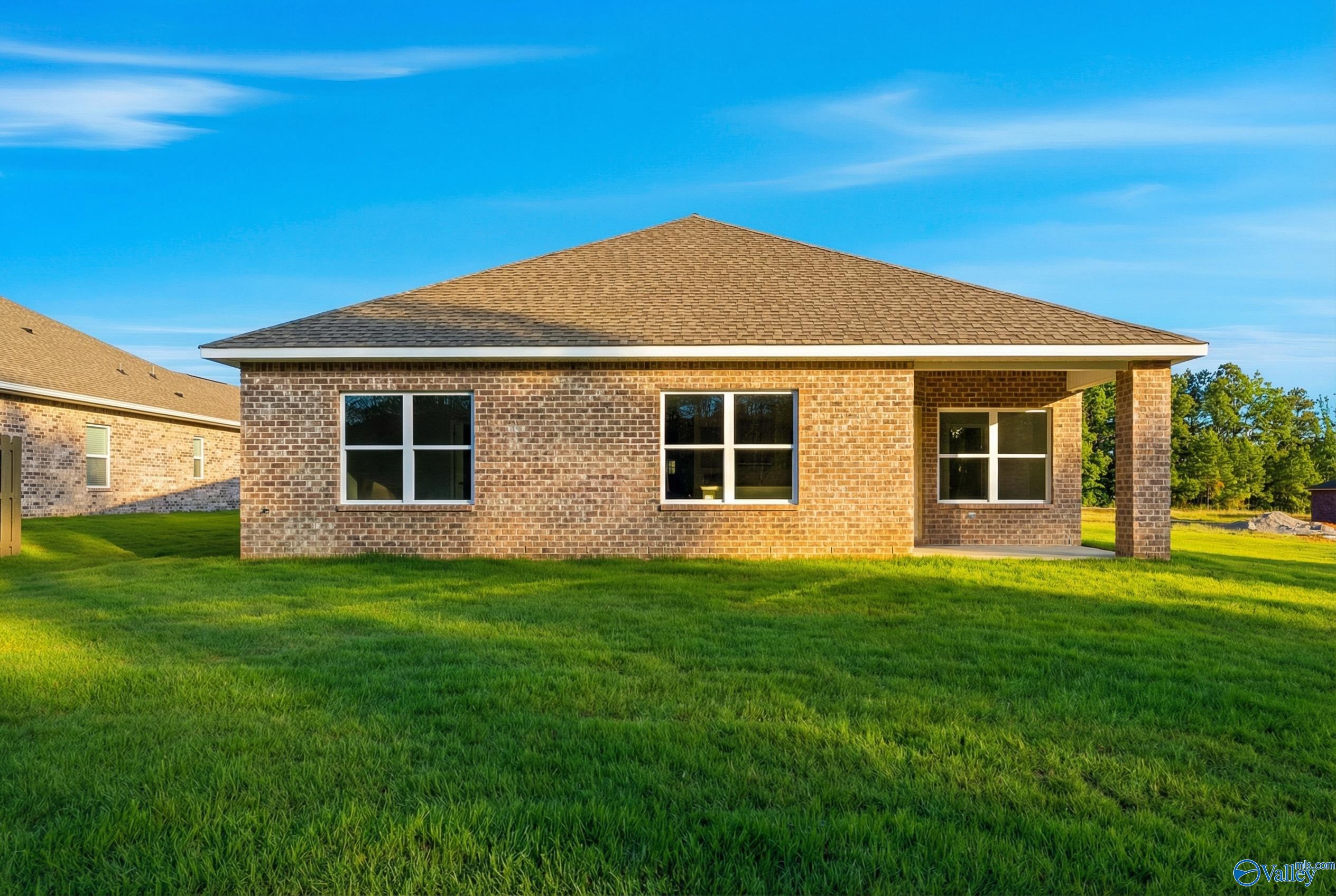 Single-story brick 4-bedroom home with gabled roof, large windows, and covered porch on lush green lawn in The Highlands, Arab, Alabama