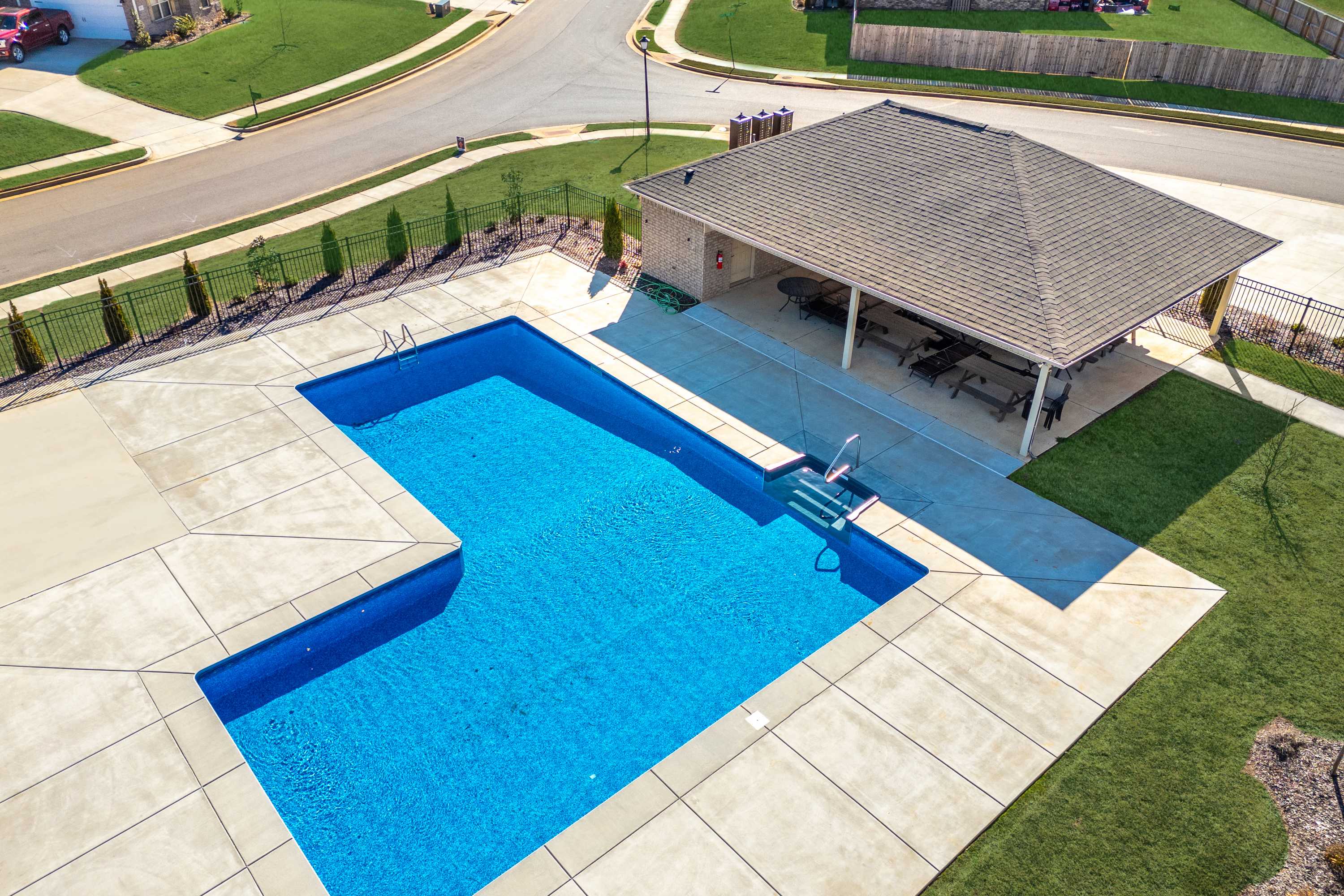 Aerial view of L-shaped blue swimming pool at Ivy Hills in Toney Alabama with covered pavilion and lounge chairs