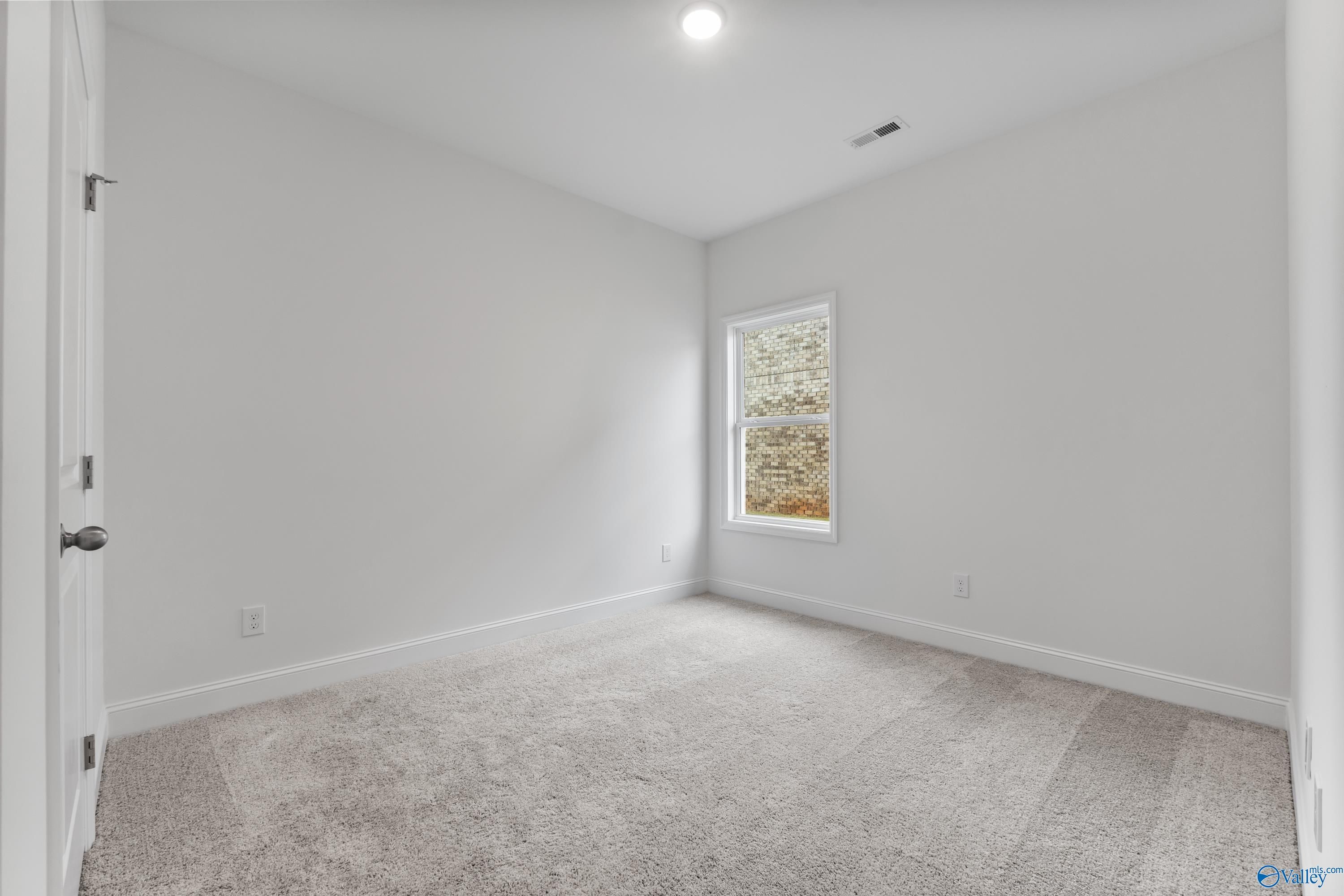 Empty bedroom with white walls, carpet flooring, large window, and open door in Davidson Homes The Asheville C, New Market, Alabama