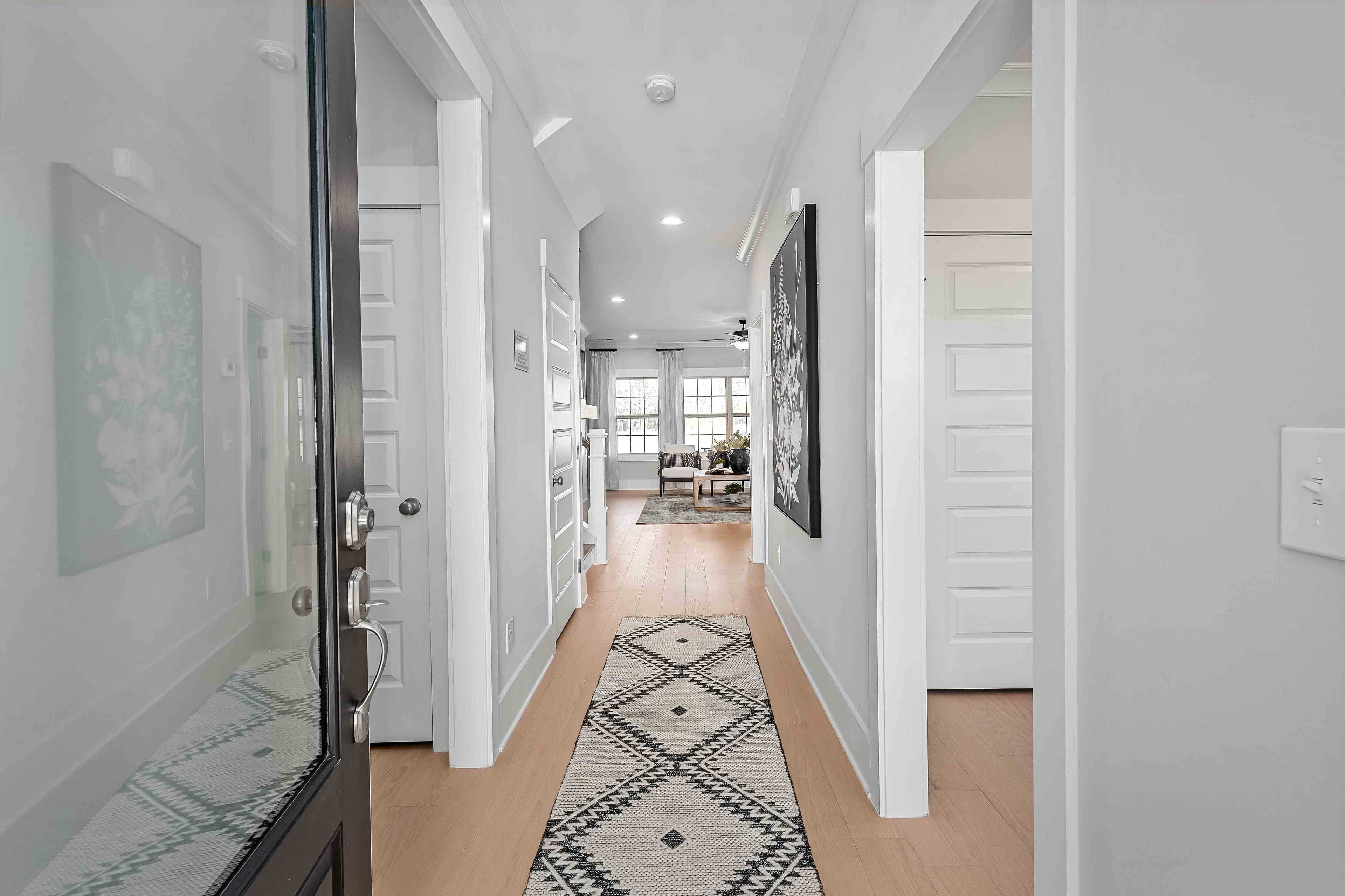 Spacious hallway in Cain Park home, Hartselle AL with hardwood floors, geometric runner rug, white doors and abstract wall art