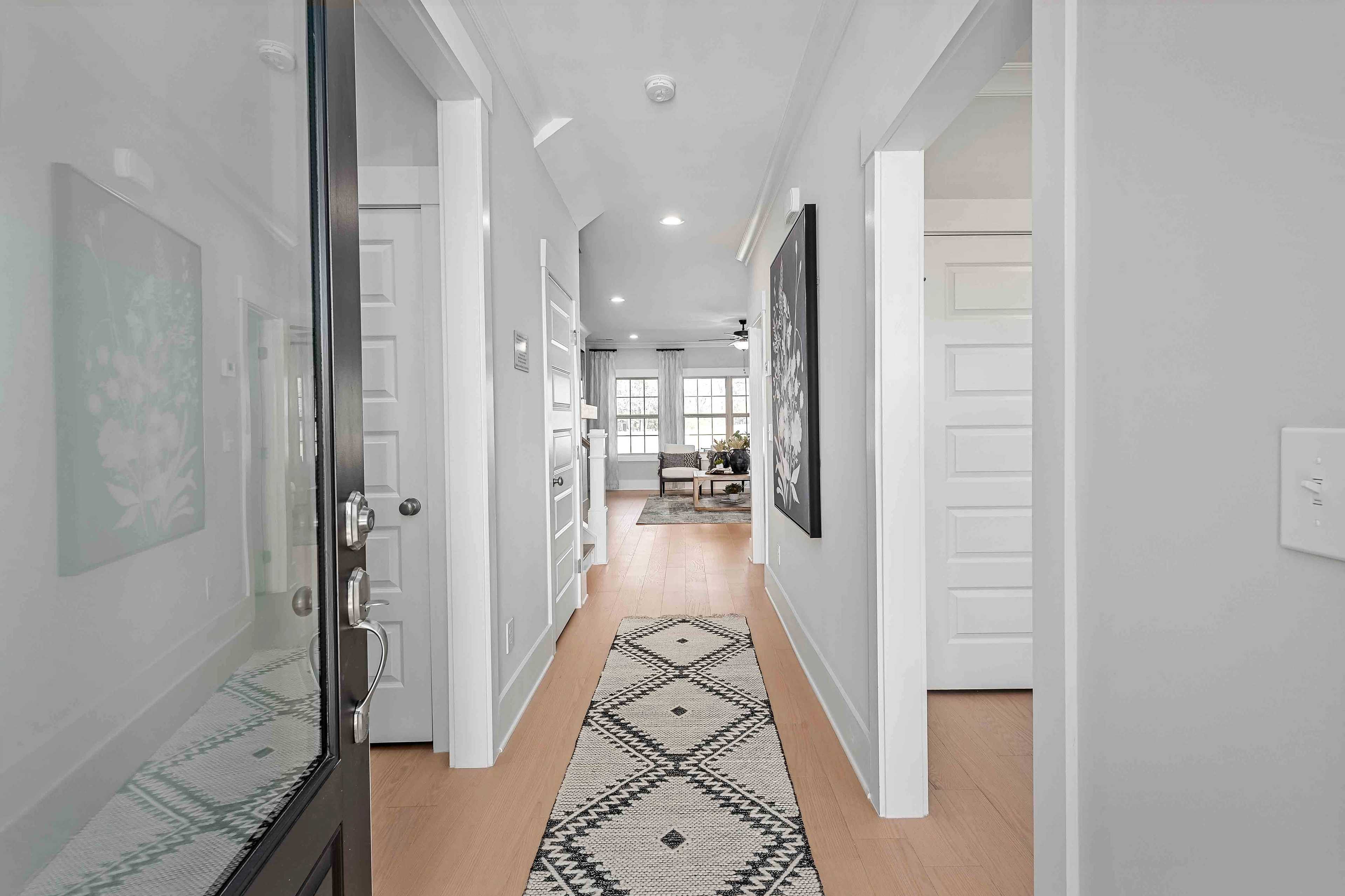 Spacious hallway in Cain Park home, Hartselle AL with hardwood floors, geometric runner rug, white doors and abstract wall art