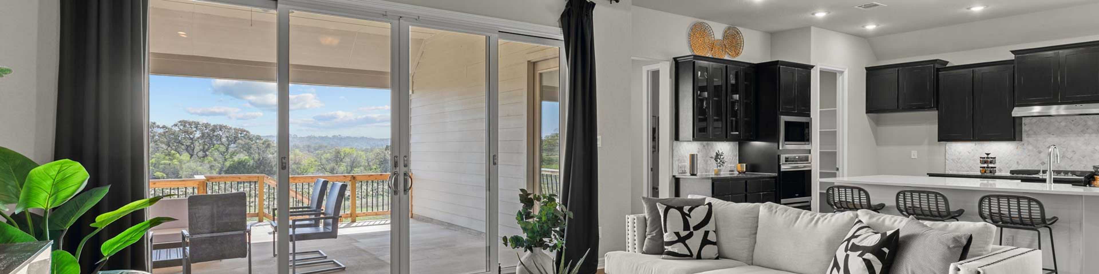 Spacious open-concept living room at Potranco Oaks in Castroville TX with hardwood floors modern sofa sliding doors to scenic patio and sleek kitchen