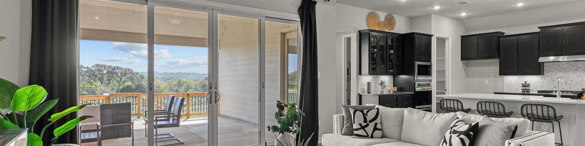 Spacious open-concept living room at Potranco Oaks in Castroville TX with hardwood floors modern sofa sliding doors to scenic patio and sleek kitchen