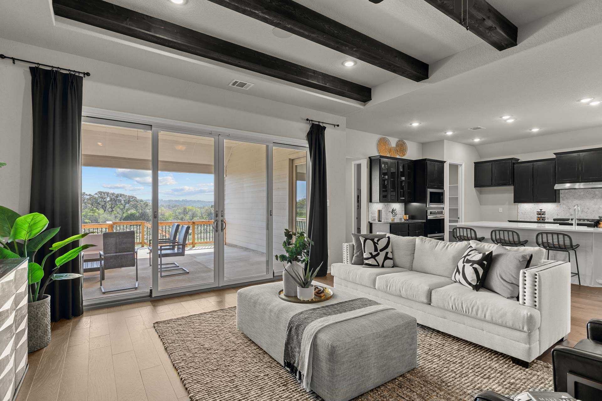 Spacious open-concept living room in The Summerlin B featuring modern kitchen island, beige sofa, and sliding doors to Texas patio view