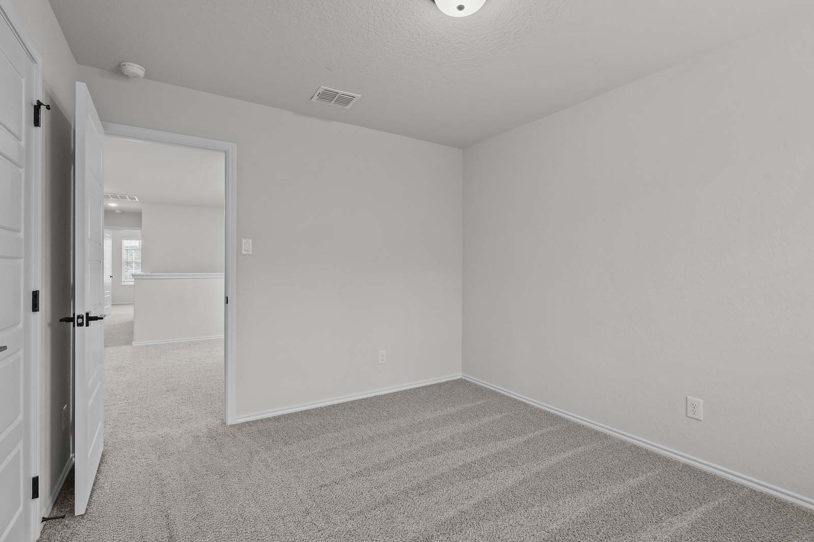 Spacious bedroom in The Florence B model featuring neutral carpet and an open doorway to the upper-level hallway.