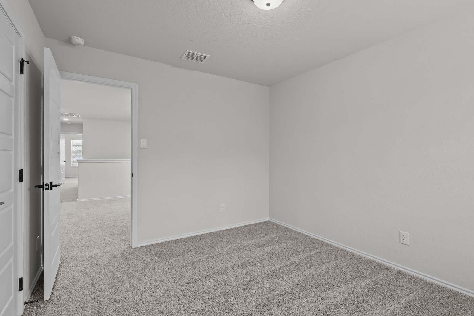 Spacious bedroom in The Florence B model featuring neutral carpet and an open doorway to the upper-level hallway.