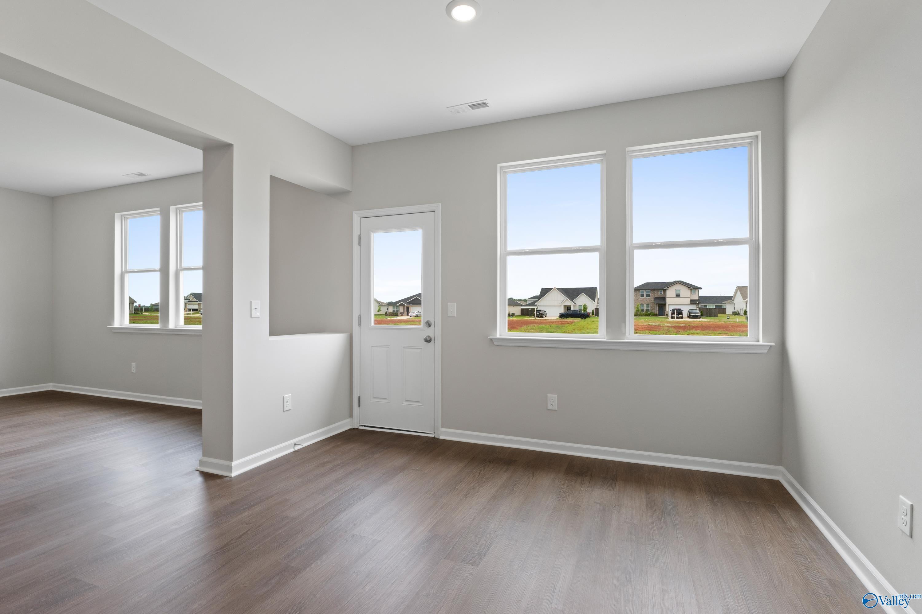 Bright sunroom with large windows, gray walls, hardwood floors, and outdoor view in Davidson Homes The Dorado, Athens Alabama