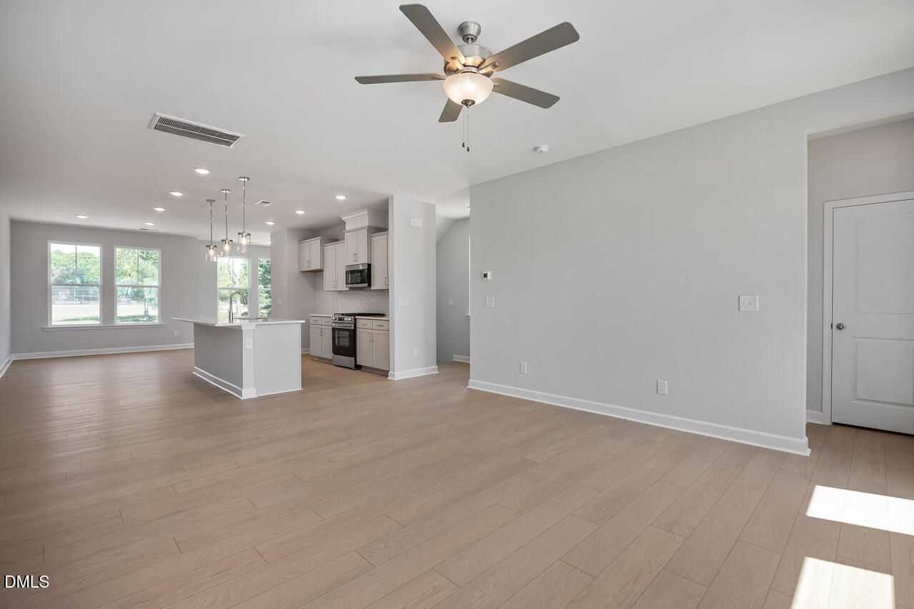 Open-concept living room and kitchen with light wood floors in The Mitchell floor plan at Camden Park, Knightdale, NC.