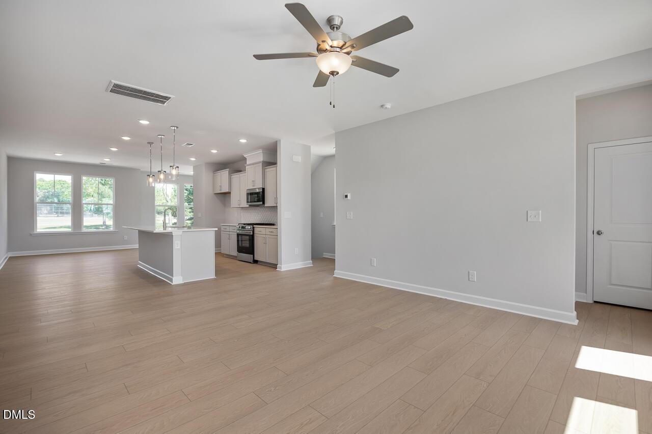 Open-concept living room and kitchen with light wood floors in The Mitchell floor plan at Camden Park, Knightdale, NC.