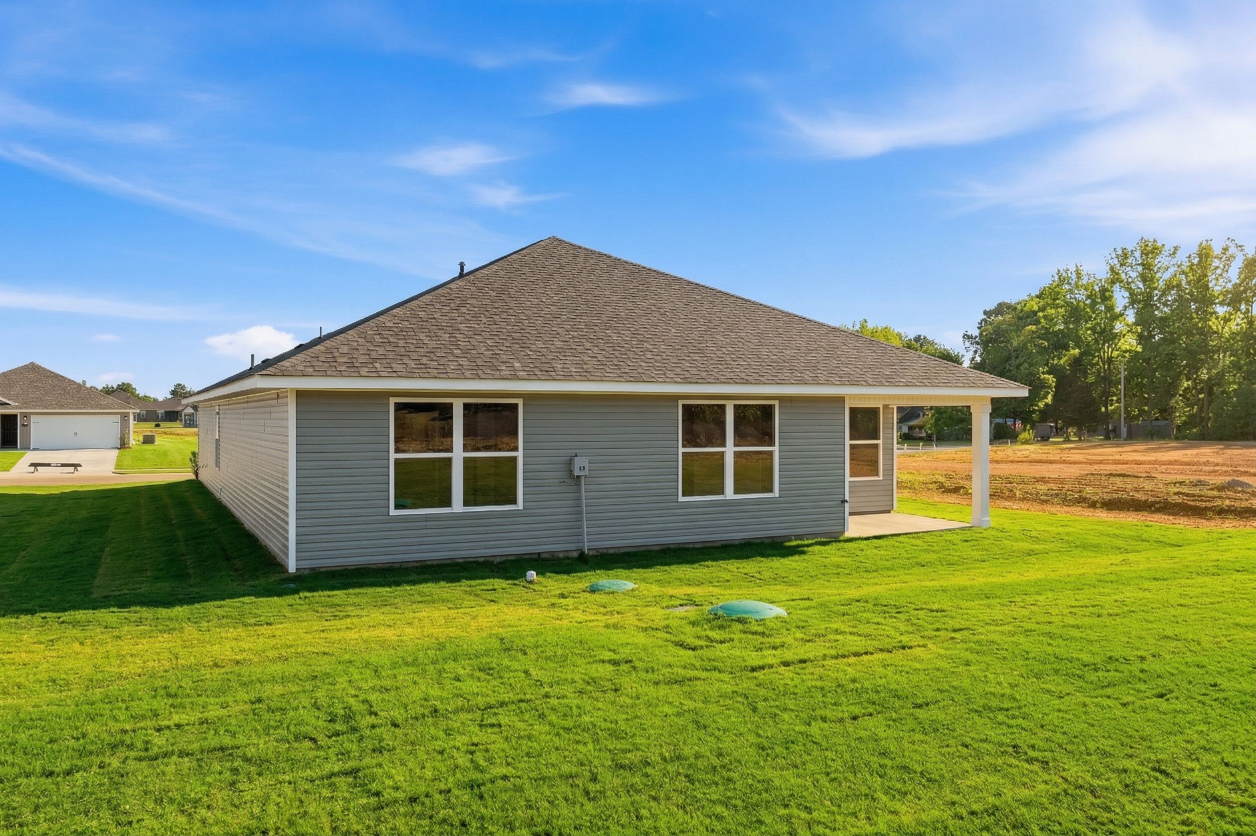 Gray-sided modern home side exterior at Chapel Hill in Athens Alabama with covered porch, double windows, and lush green lawn