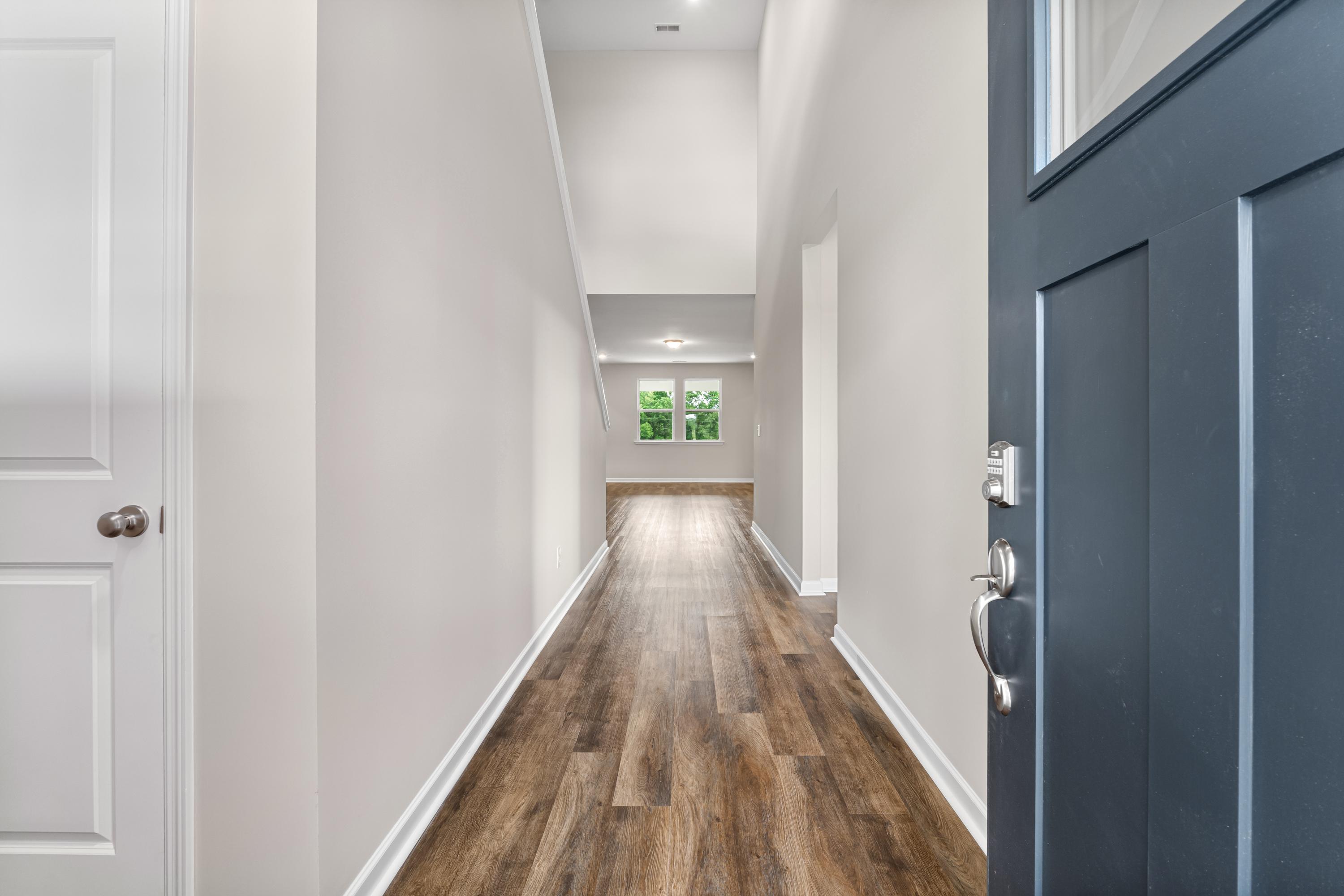Spacious entry hallway in The Haven E home with light wood floors, white walls, and blue front door