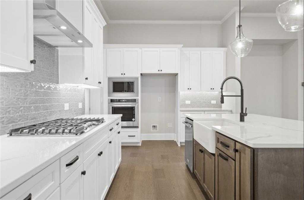 Modern white kitchen with quartz island, stainless appliances, and subway tile backsplash in Davidson Homes Seaside A, Woodstock GA
