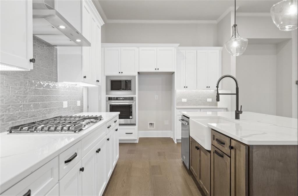 Modern white kitchen with quartz island, stainless appliances, and subway tile backsplash in Davidson Homes Seaside A, Woodstock GA