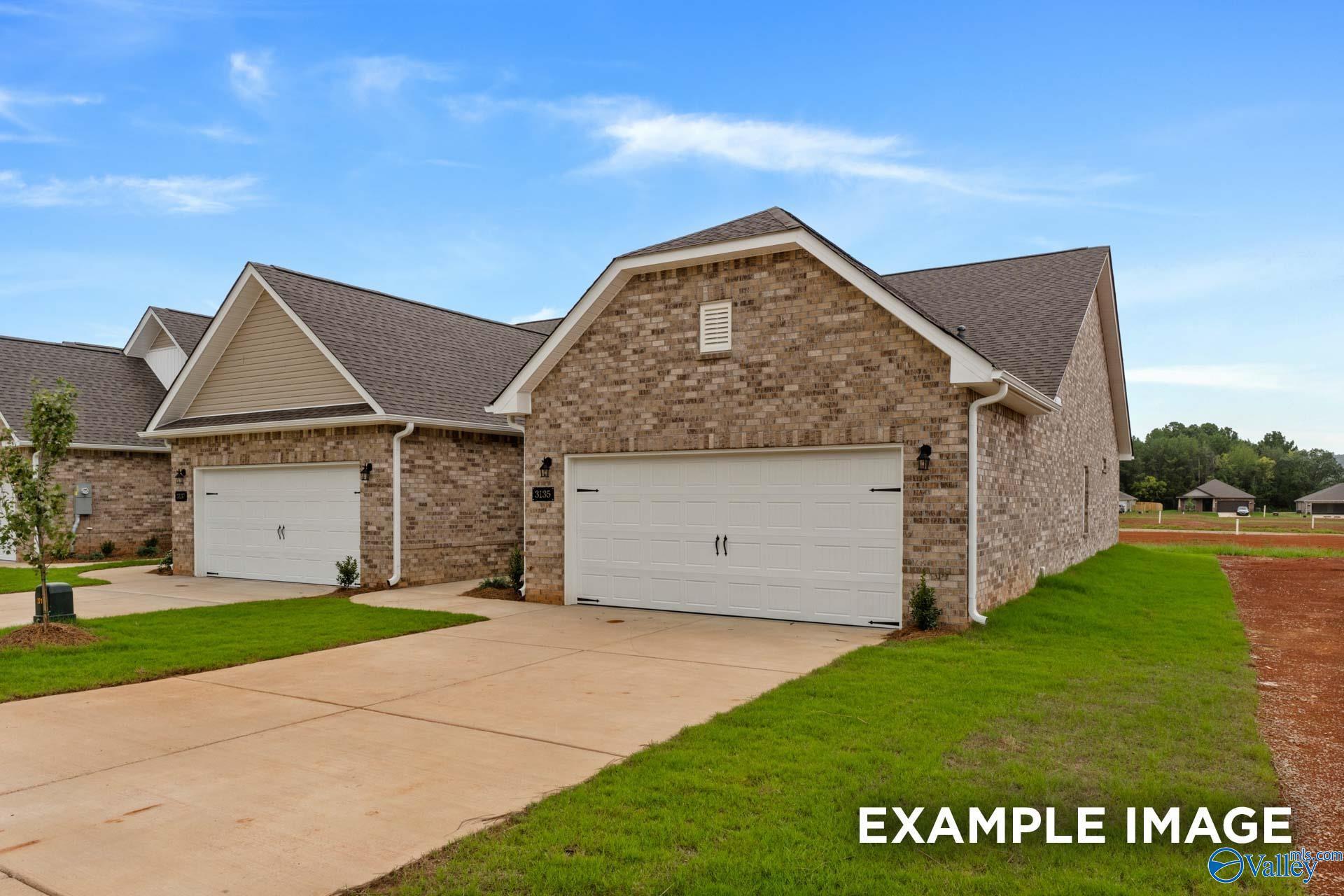 Brick single-story home with 2-car garage, shingled roof, and driveway in The Retreat at Hollon Meadow, Decatur, Alabama
